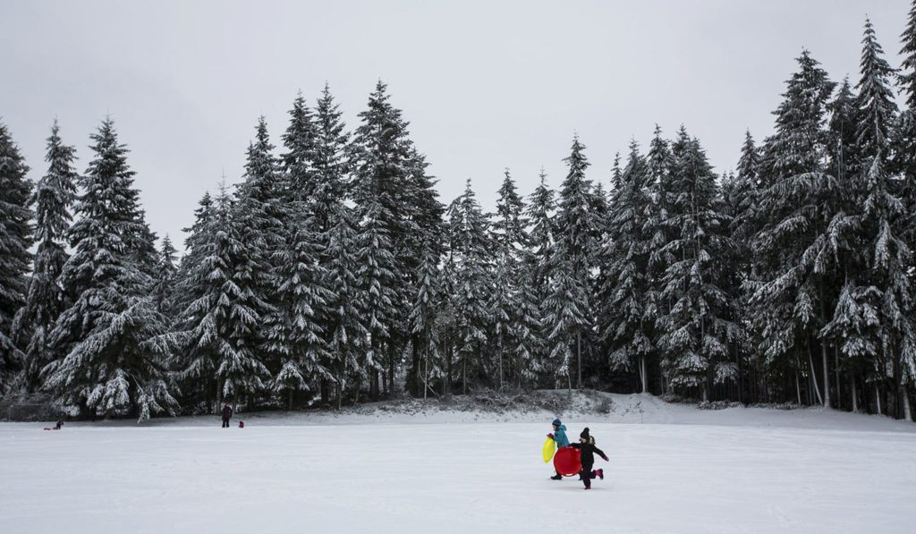 Katelynn Fitzgerald and Tegan Trefey, both 9, race through a snow-covered field at College Place Middle School on Monday in Lynnwood after a storm brought several inches, closing schools throughout the county. (Daniella Beccaria / The Herald)
