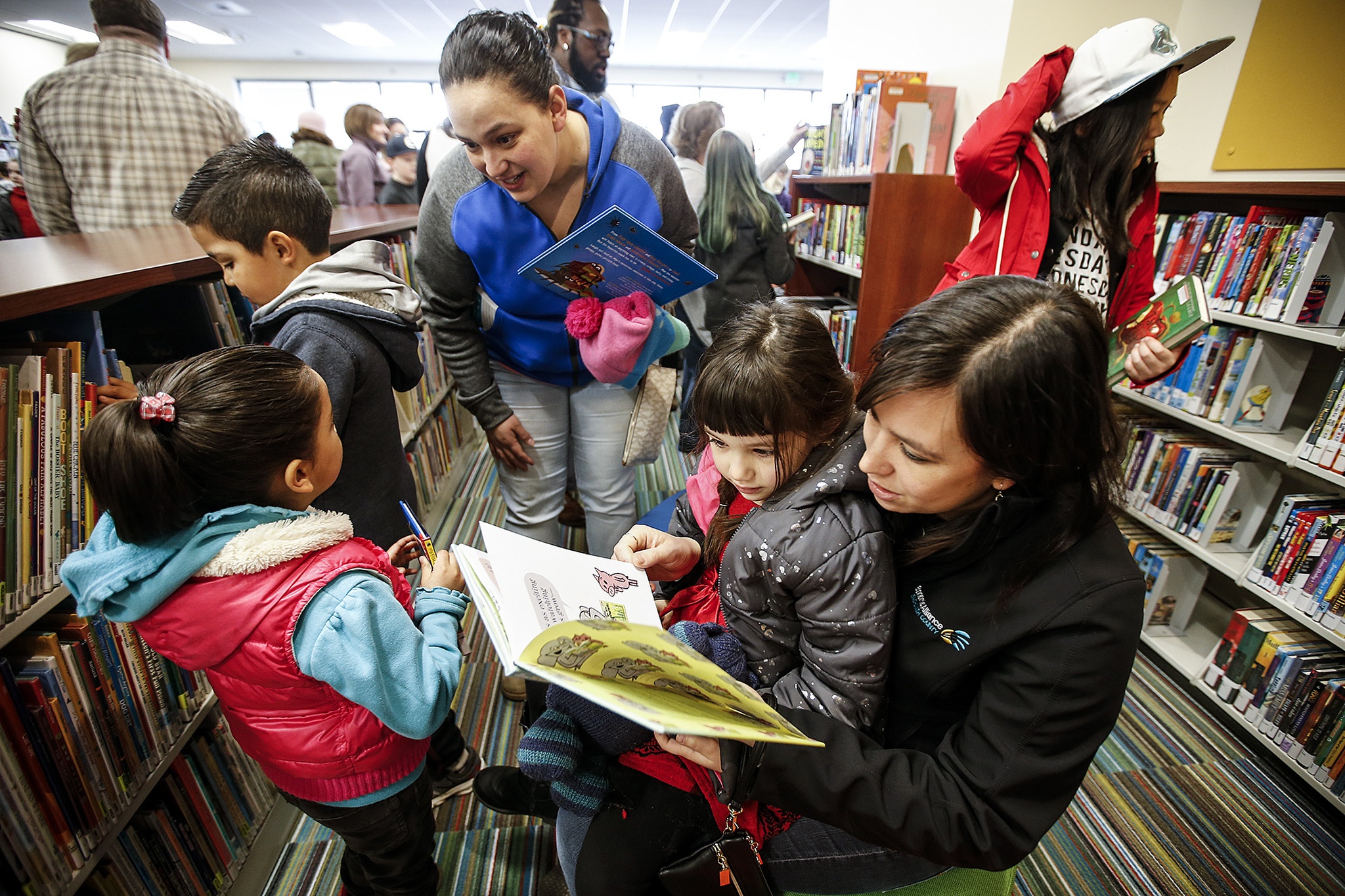 Nicole Amor (right), of Everett, reads with her daughter, Mia, 5, during the grand opening of Mariner Library on 128th Street SW in Everett on Saturday. (Ian Terry / The Herald)