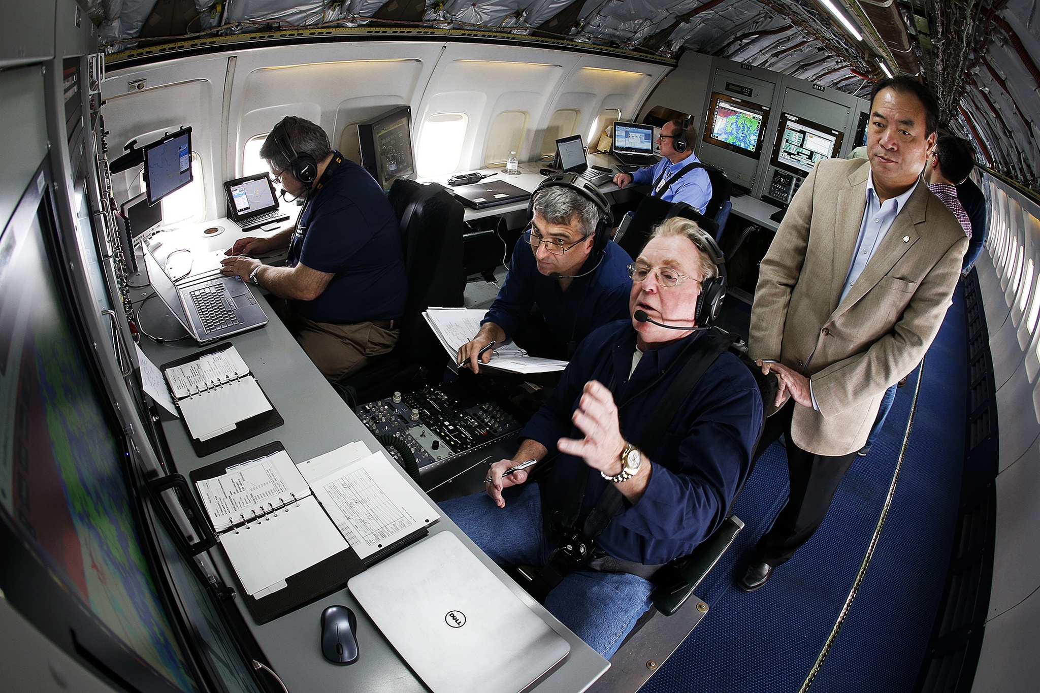 In the flight station of a Honeywell flight test plane, NASA researcher Brian Baxley (center) goes over incoming data sets with Boeing engineer Dan Boyle (center right) as NASA project manager Leighton Quon (right) looks on during a flight on Thursday from Seattle to Moses Lake to test new NextGen technologies that would allow for more streamlined consecutive landings of commercial airplanes. The technology, which improves the ability of planes to share location information, would allow for decreased spacing and improved efficiency at major airports with high traffic. (Ian Terry / The Herald)