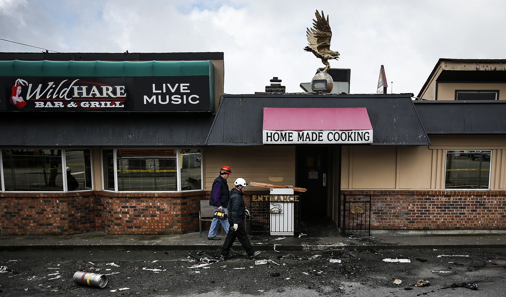 Fire investigators walk along the outside of The Village Restaurant on Thursday, Feb. 23, in Marysville. The restaurant was heavily damaged by a fire that broke out early Sunday, Feb. 19. (Ian Terry / The Herald)