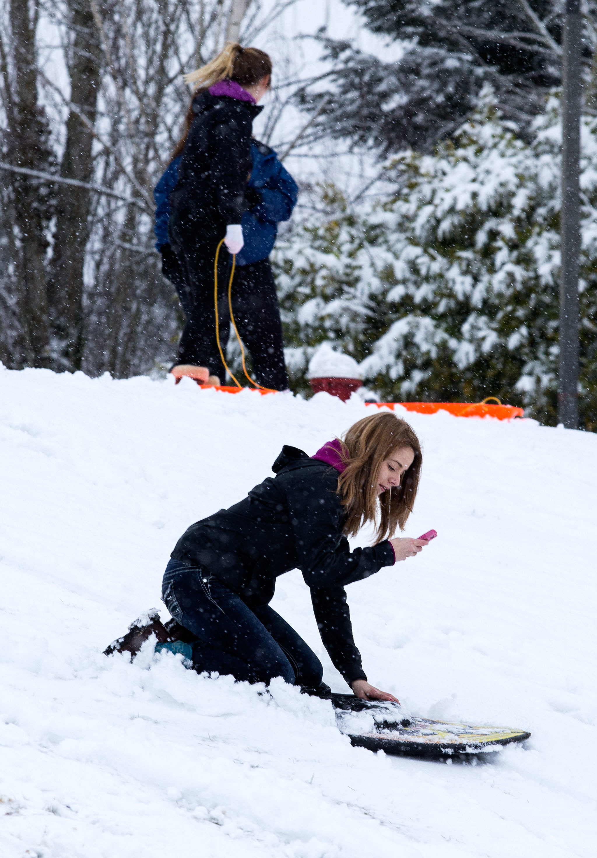 Lexi Powell, 15, uses her cellphone to record herself sledding at Stanwood High School on Monday. (Andy Bronson / The Herald)
