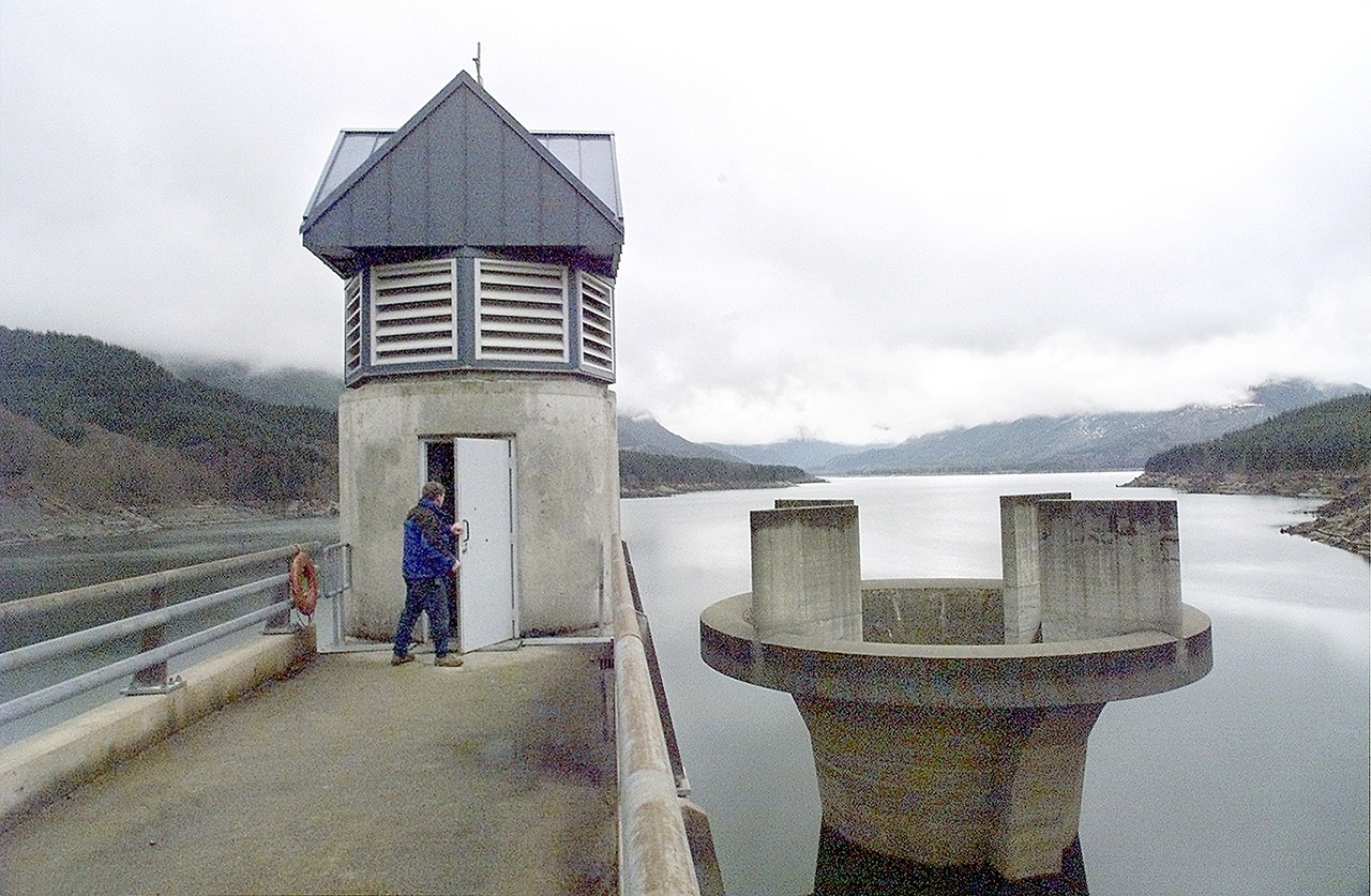 Snohomish County PUD Principal Engineer Danny Miles enters the 200-foot-tall access shaft at the Spada Lake Culmback Dam in 2001. To the the right is the morning glory spillway. (Justin Best / Herald file)