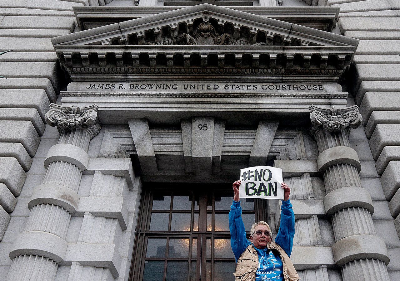 Karen Shore holds up a sign outside of the 9th U.S. Circuit Court of Appeals in San Francisco on Tuesday. A panel of appeals court judges reviewing President Donald Trump’s travel ban hammered away Tuesday at the federal government’s arguments that the states cannot challenge the order. (AP Photo/Jeff Chiu)