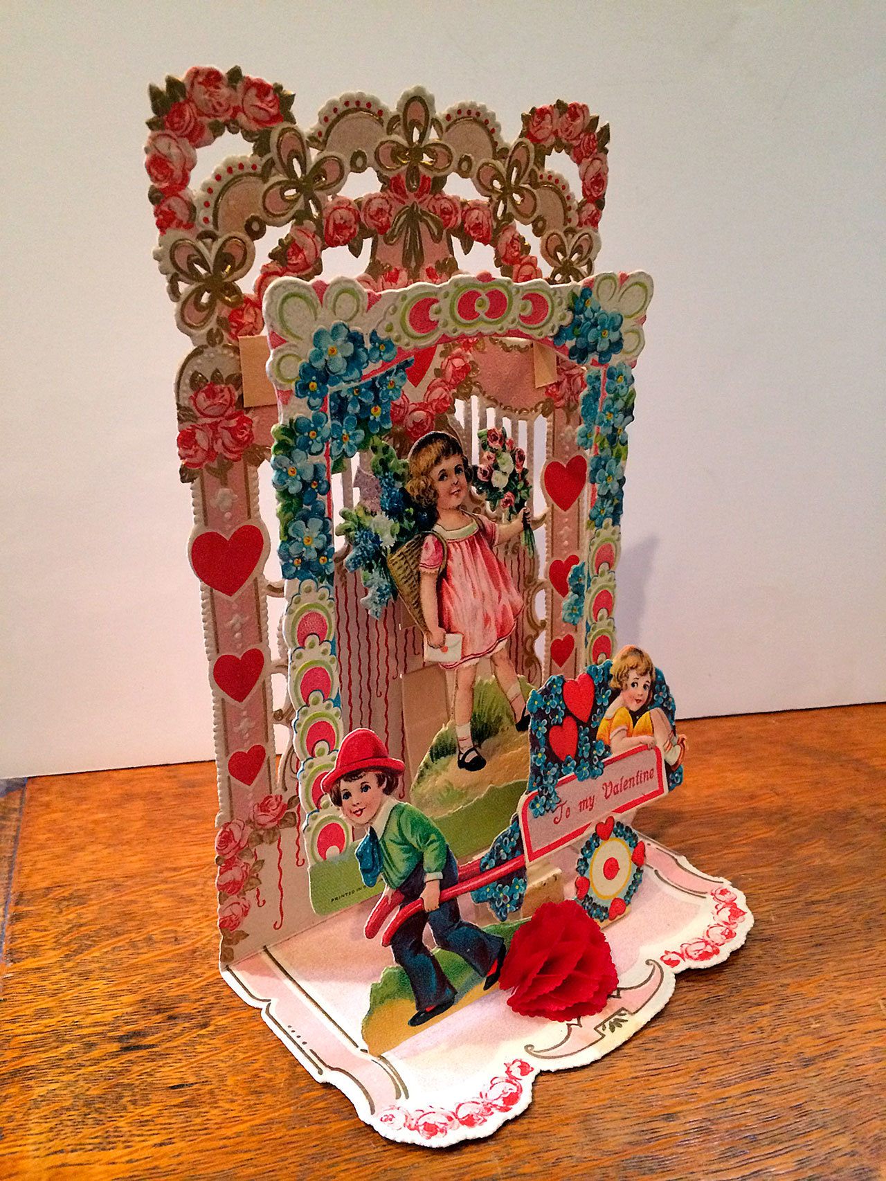 This handmade 1930s card is made from store-bought paper lace and features small chromolithographed pictures of children and flowers. The printed cardboard background is made to fit in an envelope. A collector bought it for $25 about 1980 and felt the message “To Miss Nash” on the back added to the value. It would cost about $50 today. (Cowles Syndicate Inc.)