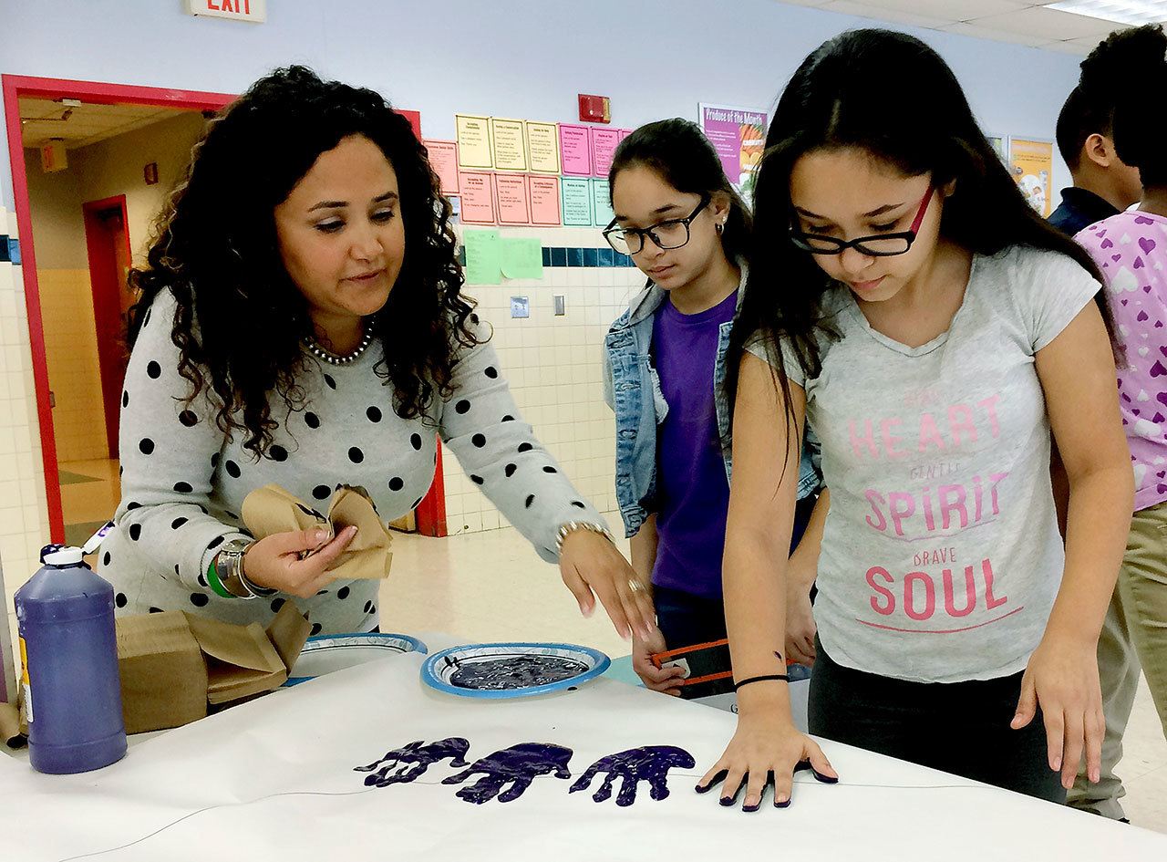 Nelba Marquez-Greene (left) helps 10-year-old Araceli Buchko put her hand print inside a giant paper heart as part of Friendship Day, a social and emotional learning activity at the Chamberlain Elementary School in New Britain, Connecticut. (AP Photo/Pat Eaton-Robb)