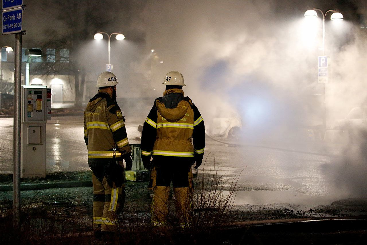 Firefighters on Monday survey the scene where riots that broke out in a predominantly immigrant Stockholm suburb after officers arrested a suspect on drug charges. (Christine Olsson/TT News Agency via AP)