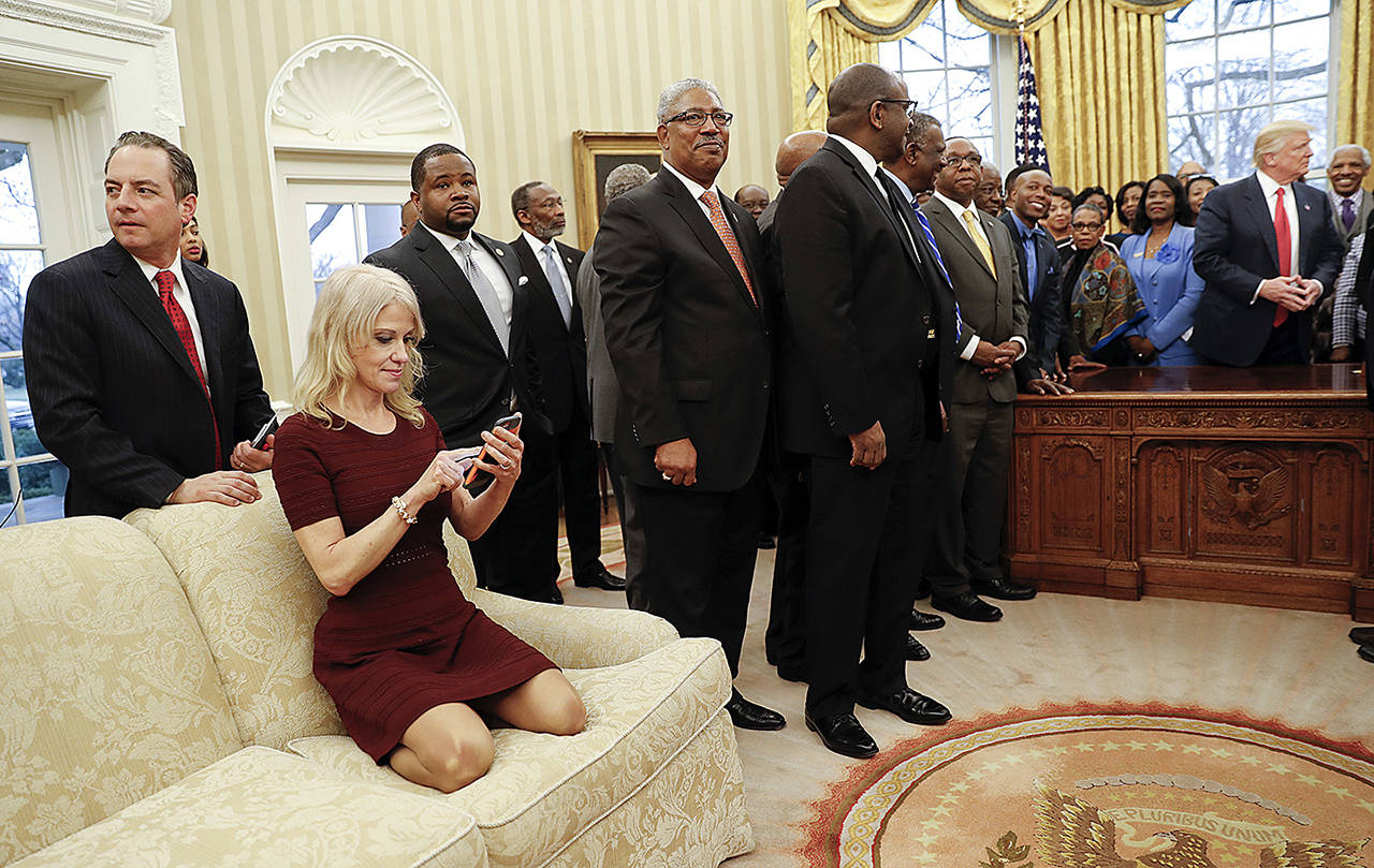 President Donald Trump meets with leaders of Historically Black Colleges and Universities (HBCU) in the Oval Office of the White House in Washington on Monday, Feb. 27, while Counselor to the President Kellyanne Conway kneels on the couch. Chief of Staff Reince Priebus stands behind Conway. (AP Photo/Pablo Martinez Monsivais)