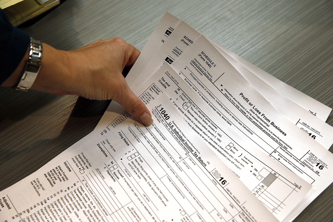 In this Jan. 14 photo, tax professional and tax preparation firm owner Alicia Utley reaches for hard copies of tax forms while working to stay caught up on a Saturday at the start of the tax season rush, in her offices at Infinite Tax Solutions, in Boulder, Coloroado. (AP Photo/Brennan Linsley)