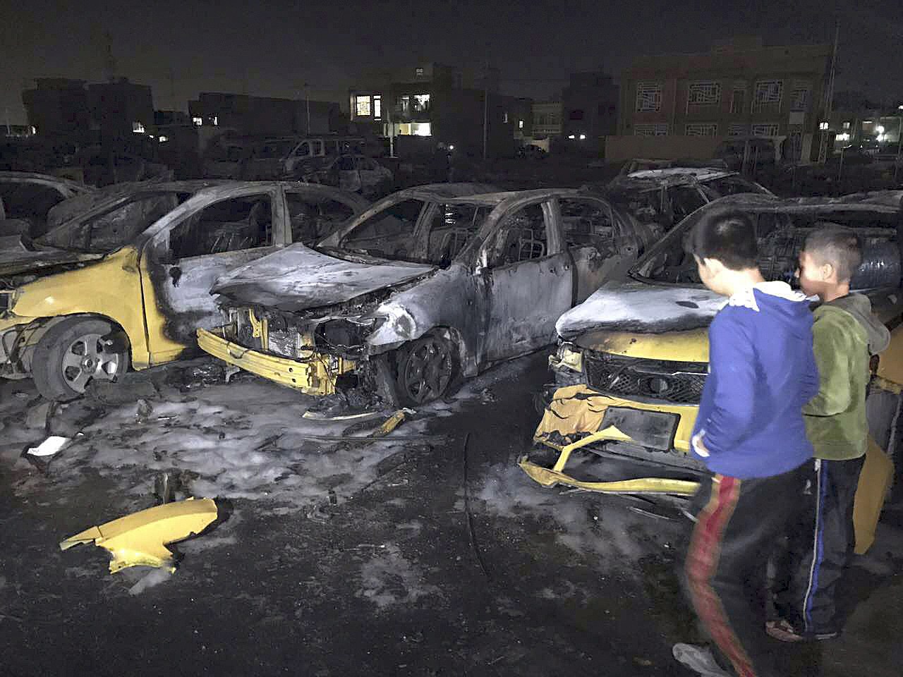 Civilians gather at the site of a car bomb in a used car dealer’s parking lot in the southwestern al-Bayaa neighborhood in Baghdad, Iraq, on Thursday, Feb. 16. (AP Photo/ Ali Abdul Hassan)