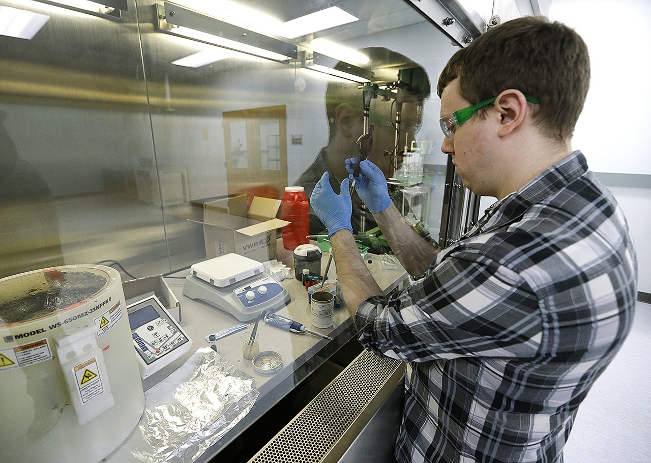 Caleb Ogier, a PhD student in mechanical engineering at the University of Washington, works in a fume hood with ink used to print electrical circuits at the newly opened Washington Clean Energy Testbeds lab housed in the University of Washington’s Clean Energy Institute, on Monday, Feb. 13, in Seattle. (AP Photo/Ted S. Warren)