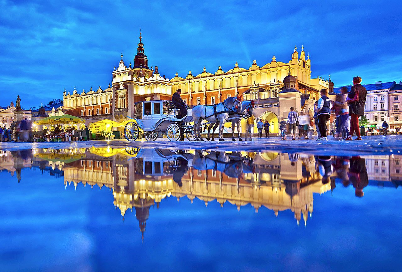 A rain puddle reflects the floodlit charm of Cloth Hall, one of several major buildings on Krakow’s Main Market Square.