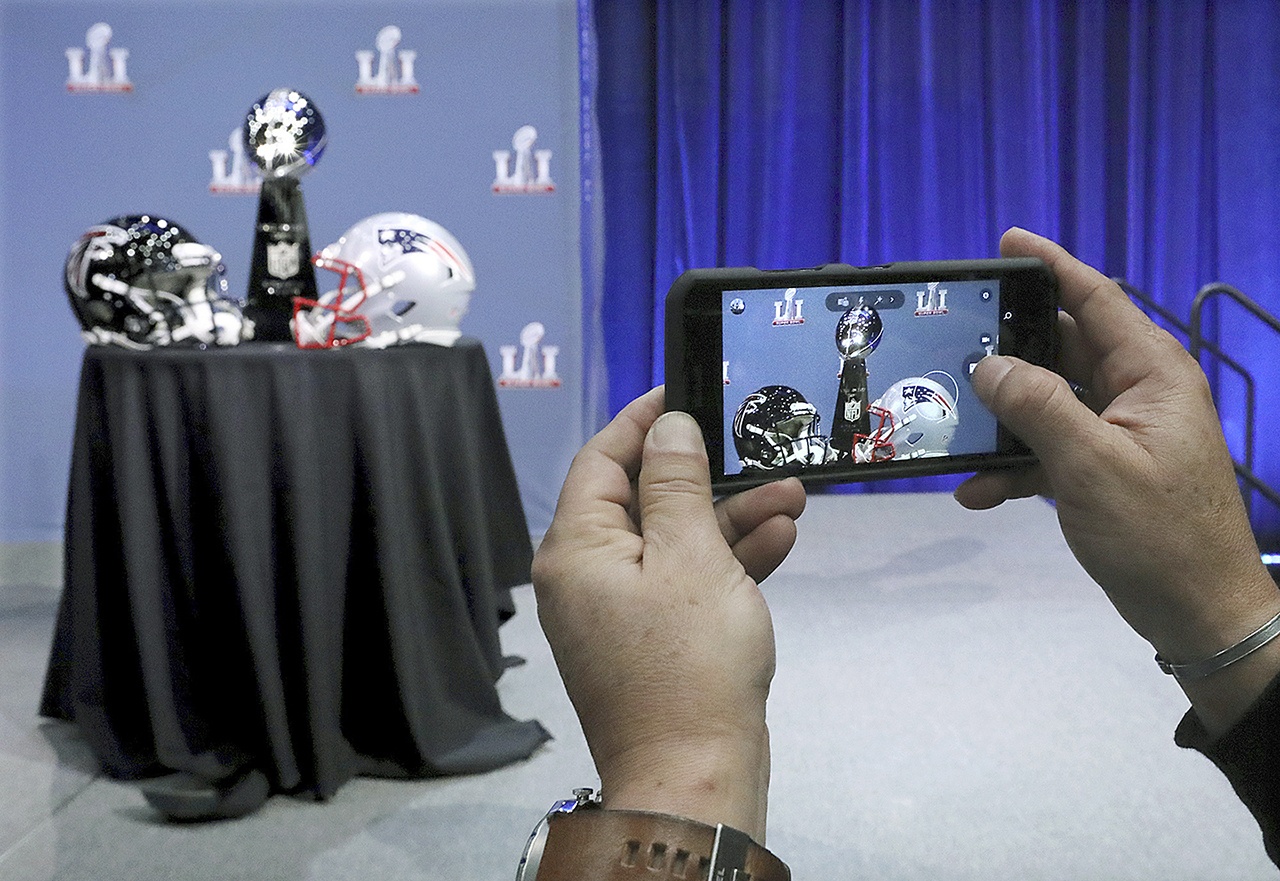 In this Feb. 1 photo, an attendee snaps a photo of the Vince Lombardi Trophy and team helmets during NFL Commissioner Roger Goodell’s news conference for Super Bowl 51, in Houston. (Curtis Compton/Atlanta Journal-Constitution via AP, File)