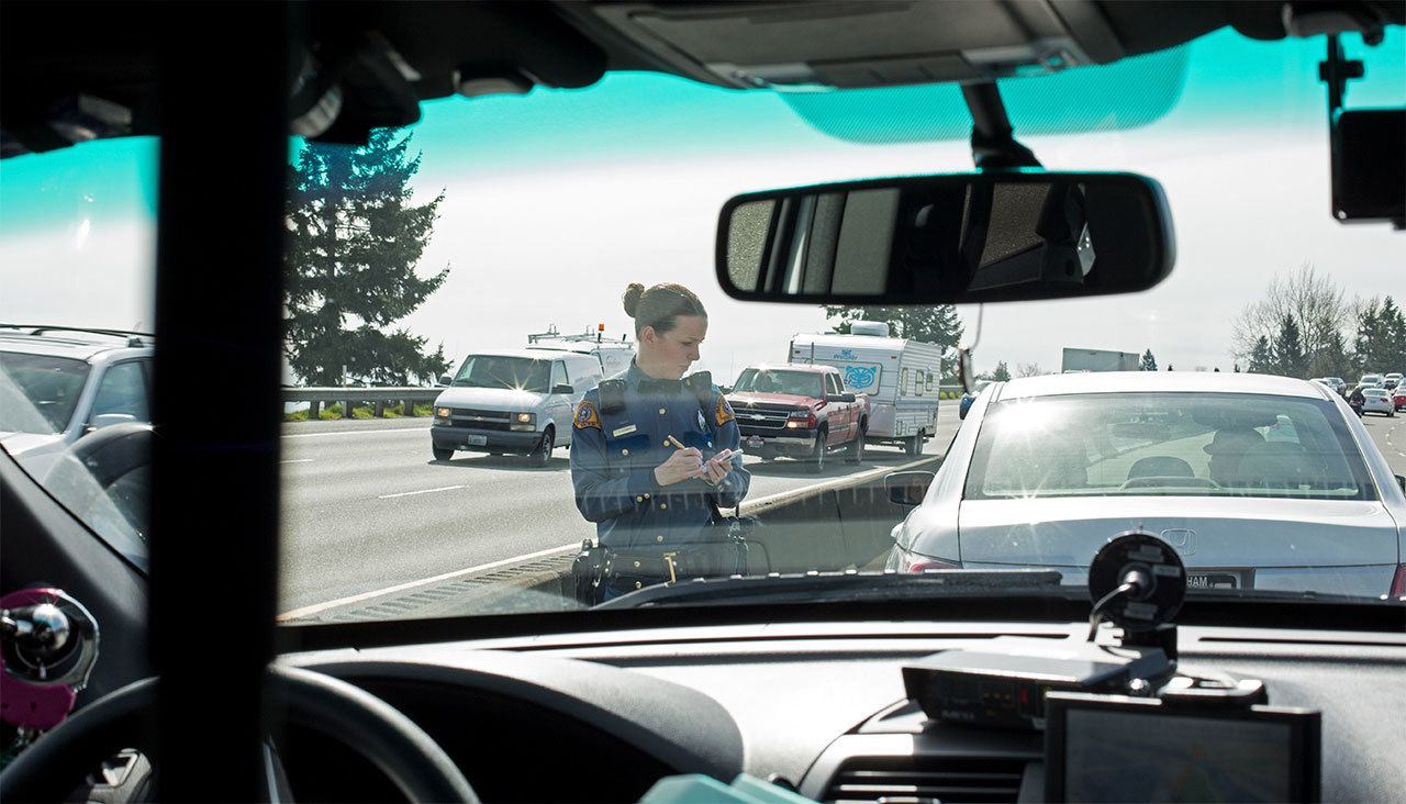Washington State Patrol Trooper Heather Axtman takes down the license of a car after giving the driver a warning in March 2016 on I-5 in Everett. (Andy Bronson / Herald file)