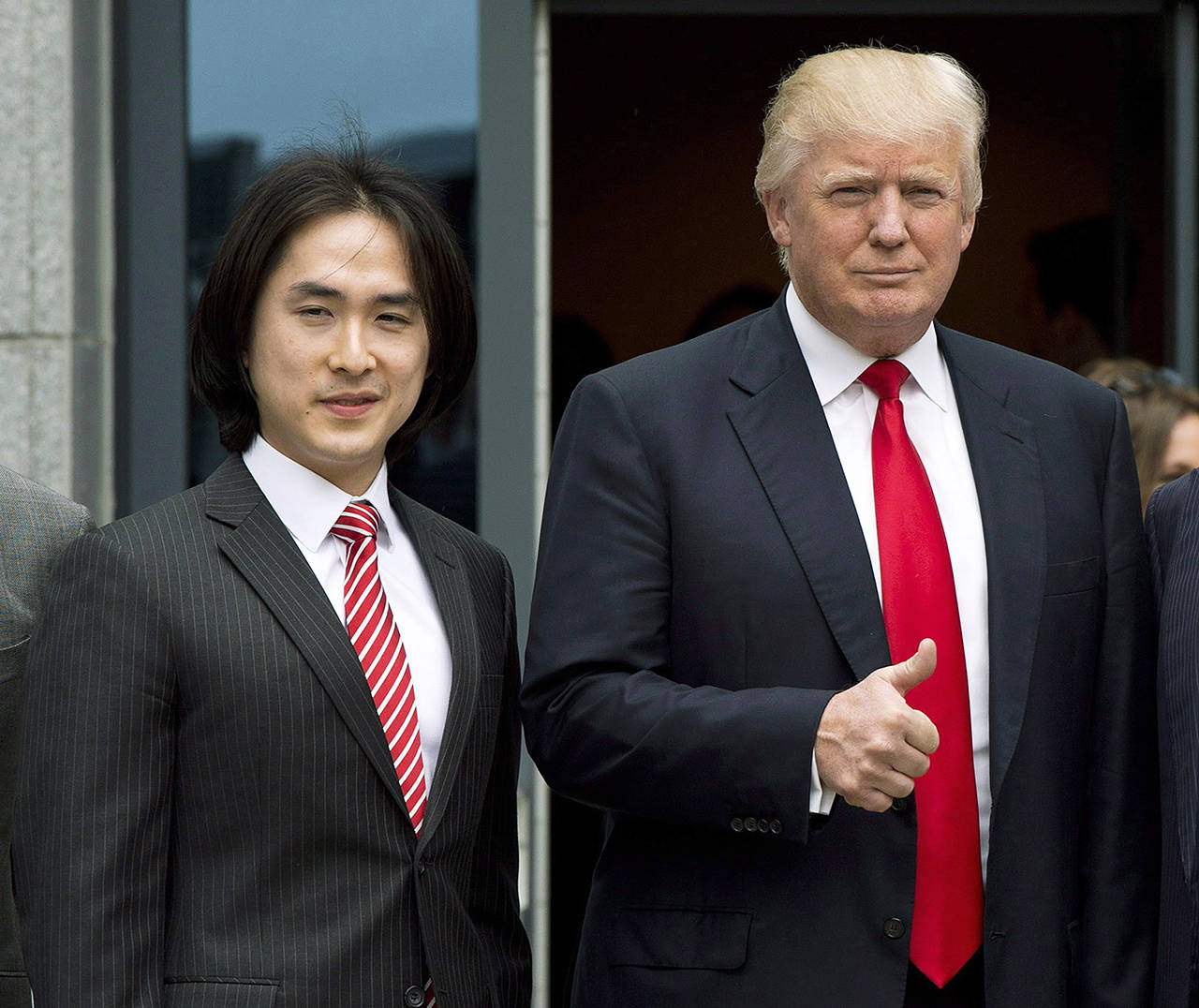 In this 2013 photo, Donald Trump gives a thumbs-up as he poses with Tiah Joo Kim, CEO and president of Holborn Group, upon arrival to announce the building of Trump International Hotel and Tower Vancouver in downtown Vancouver, Canada. (Jonathan Hayward/The Canadian Press via AP)