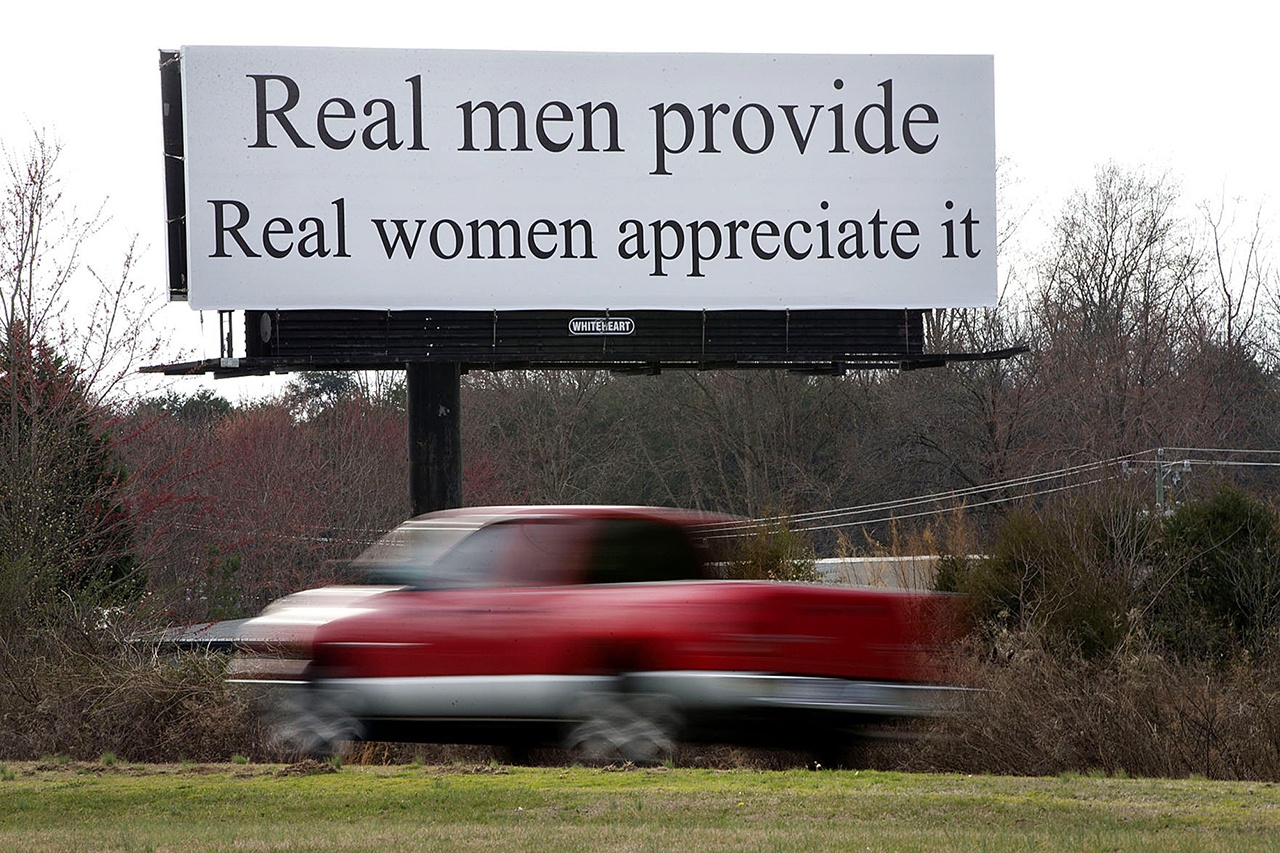 A vehicle drives by a billboard, Wednesday, Feb. 22, near Greensboro, North Carolina. The billboard reads, “Real men provide. Real women appreciate it.” Women are planning this weekend to protest the billboard’s message, which they say is a slam on gender equality, according to media reports. (Andrew Krech/News & Record via AP)/