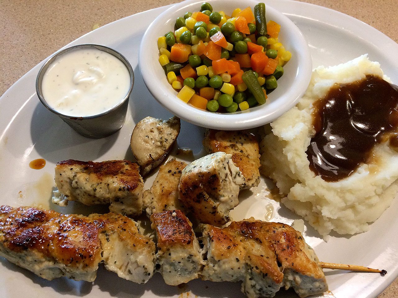 The chicken souvlaki at Brianna’s Cafe comes with a green salad, bread, potatoes, a vegetable medley and tzatziki yogurt sauce in which to dip the grilled chicken skewers. (Gale Fiege / The Herald)