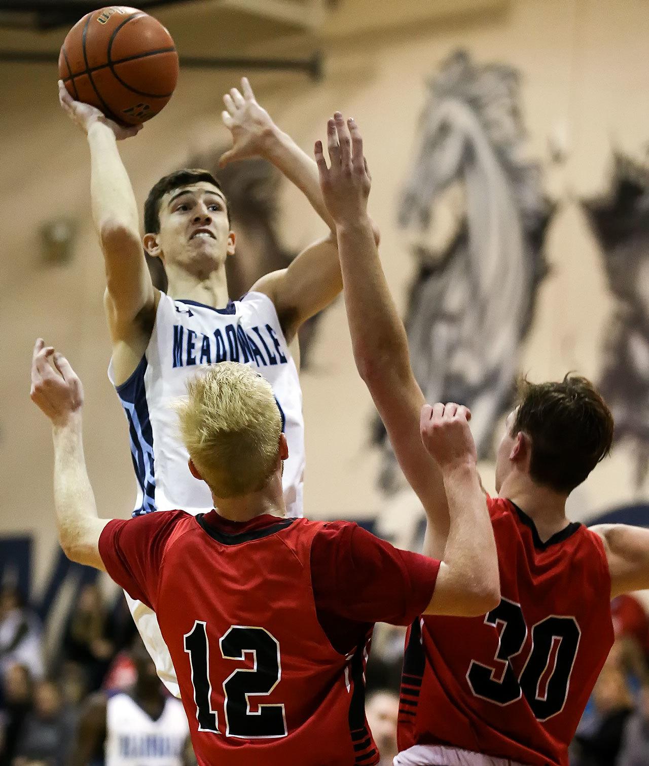 Meadowdale’s Daniel Barhoum attempts a shot over Snohomish’s Tristan MacGregor (left) and Kole Bride (right) during a 3A district play-in game Feb. 10, 2017, at Meadowdale High School in Lynnwood. The Mavericks won 66-54. (Kevin Clark / The Herald)