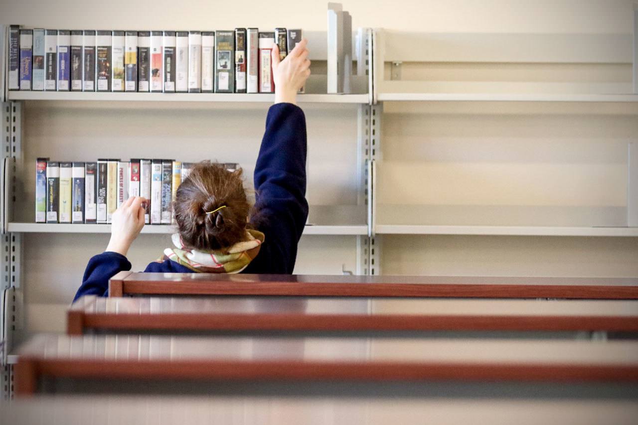 Kerry Spaulding stocks audio books at the new Mariner Library in Everett on Feb. 2. The demonstration community library will carry more than 16,000 titles, and will open Saturday. (Kevin Clark / The Herald)