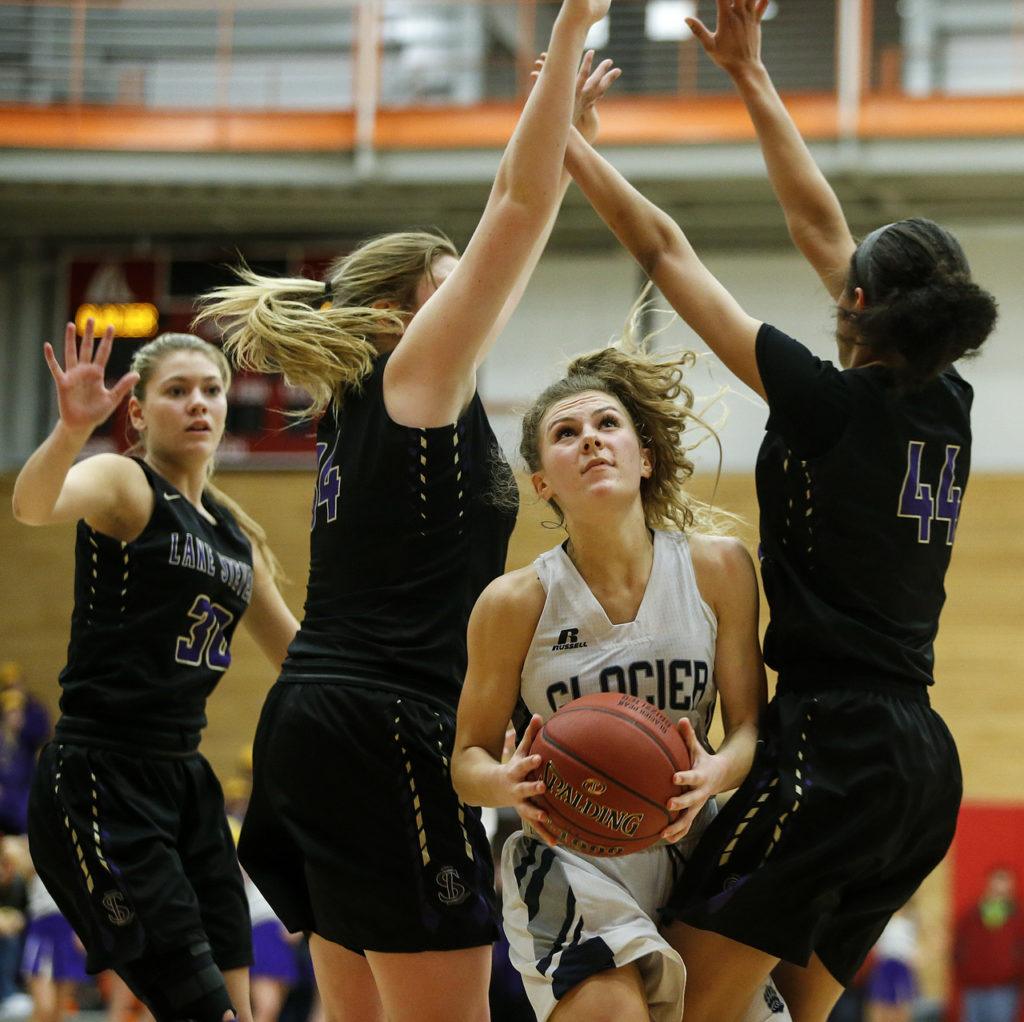 Glacier Peak’s Paisley Johnson (center) cuts through Lake Stevens defenders Marissa Walton (center left) and Kylee Griffen (right) during the Class 4A District 1 girls basketball championship game at Everett Community College on Thursday, Feb. 16. Glacier Peak went on to defeat Lake Stevens 60-41. (Ian Terry / The Herald)
