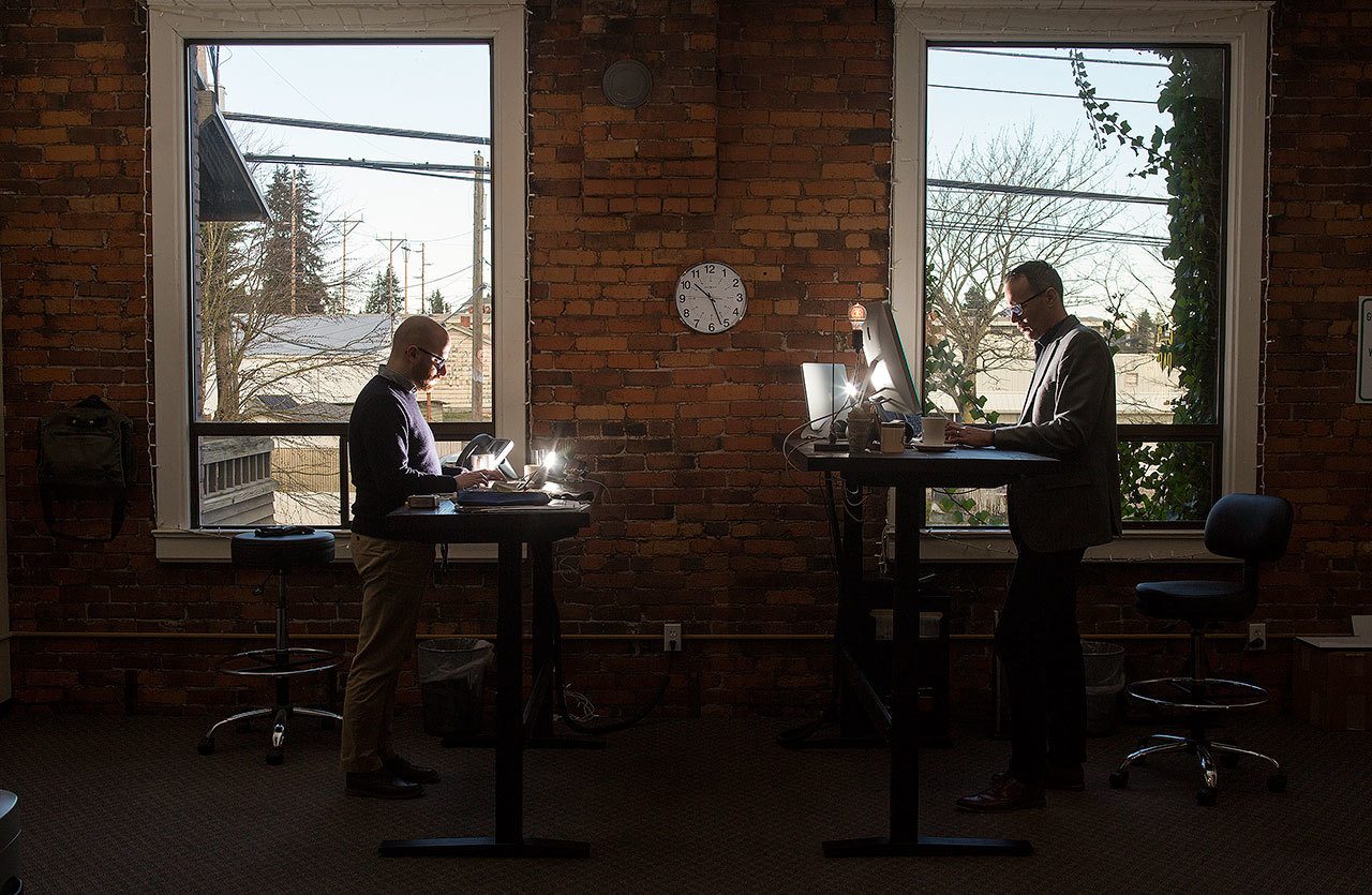 Joel DuChesne and Nathan LeMesurier, left, partners in Parking Boss, an Everett software company, work at their computers in their office on Wednesday, Jan. 11. The software company helps apartment and condo building owners deal with parking arrangements for residents, visitors and guests. (Andy Bronson / The Herald)
