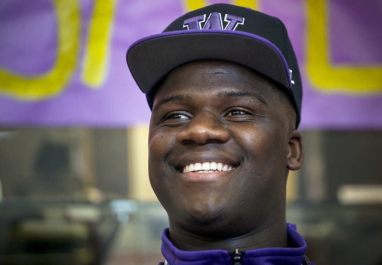 Edmonds-Woodway’s Ali Gaye dons a University of Washington hat during a signing day celebration in the school’slibrary on Wednesday. (Ian Terry / The Herald)