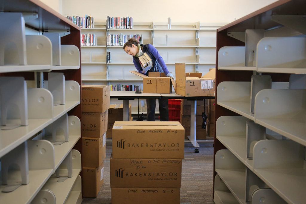 Chelsea Cooper unboxes books at the new Mariner Library in Everett on Feb. 2. The demonstration community library will carry more than 16,000 titles, and will open Saturday. (Kevin Clark / The Herald)
