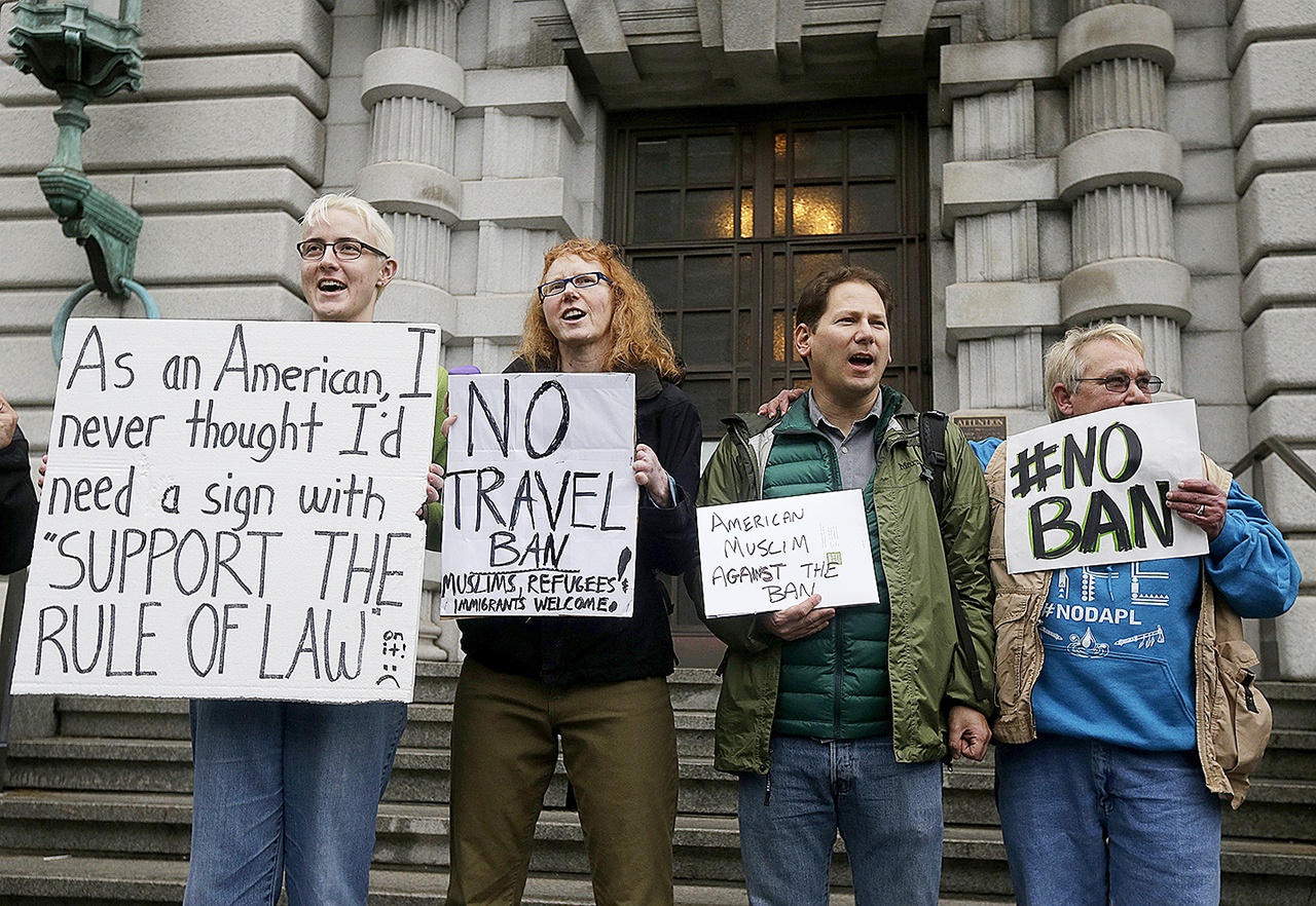 In this Feb. 7 photo, Kay Aull, from left, holds a sign and chants with Beth Kohn, Paul Paz y Mino and Karen Shore outside of the 9th U.S. Circuit Court of Appeals in San Francisco, California. (AP Photo/Jeff Chiu, File)