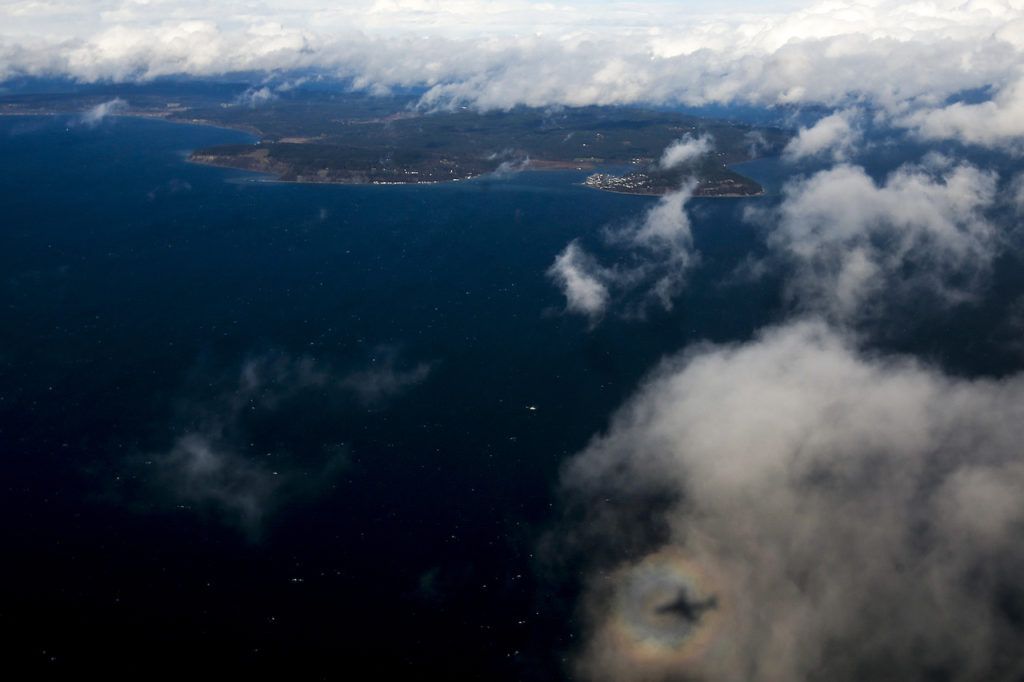 The reflection of a Honeywell test plane is seen against a cloud hovering above the Puget Sound north of Seattle on Thursday, Feb. 9. (Ian Terry / The Herald)
