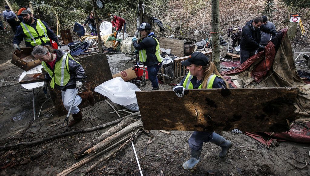 Volunteers remove debris and garbage from a homeless encampment along the Skykomish River near Monroe on Saturday, Feb. 25. Nearly 100 volunteers cleaned out the area in an event organized by Riverjunky and the Snohomish County Sheriff’s Office. (Ian Terry / The Herald)
