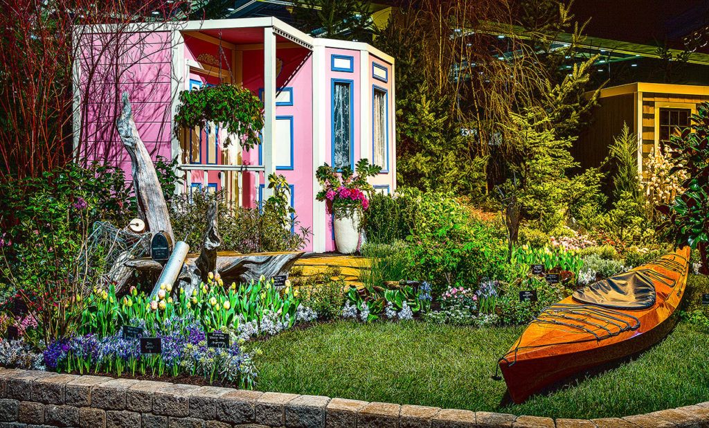 “From Sea to Shining Sea – Coupeville, Washington” is the title of this display garden from the 2016 show by Fancy Plants Gardens, Inc., in Bothell. Colorful and slightly quirky, travelers make their way to this seaside town to enjoy the spectacular natural saltwater setting. A destination for many for generations, Coupeville’s historic Blue Goose Inn Bed & Breakfast is depicted here, including its eye-catching pink-with-blue-trim exterior. Oysters, crabs and a kayak, symbolizing the ties this town has to Puget Sound, are found throughout the landscape. Metal sculptures — herons, bear, a moose and more — accentuate the Northwest flavor of Coupeville. (Northwest Flower & Garden Show)
