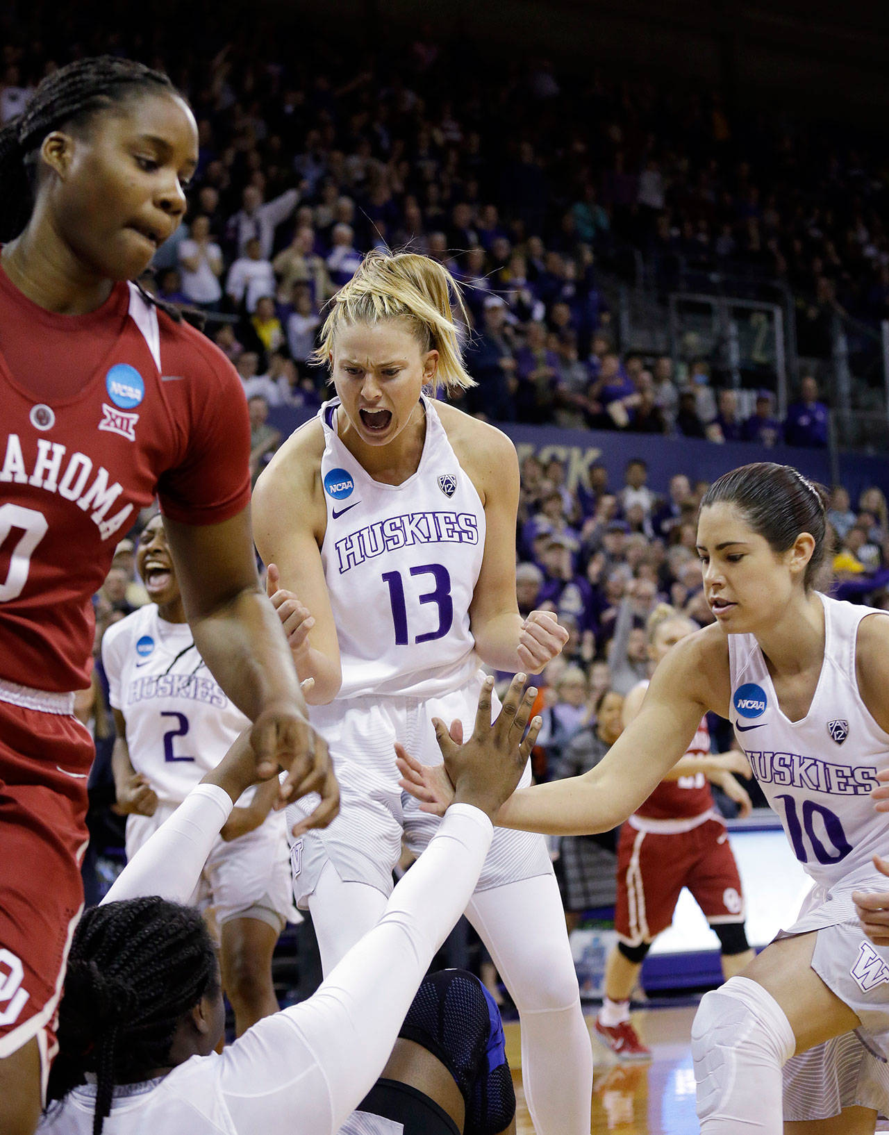 Washington’s Kelsey Plum (10) and Katie Collier (13) reach to help Chantel Osahor to her feet after she was fouled during the first half Monday’s game in Seattle. (AP Photo/Elaine Thompson)