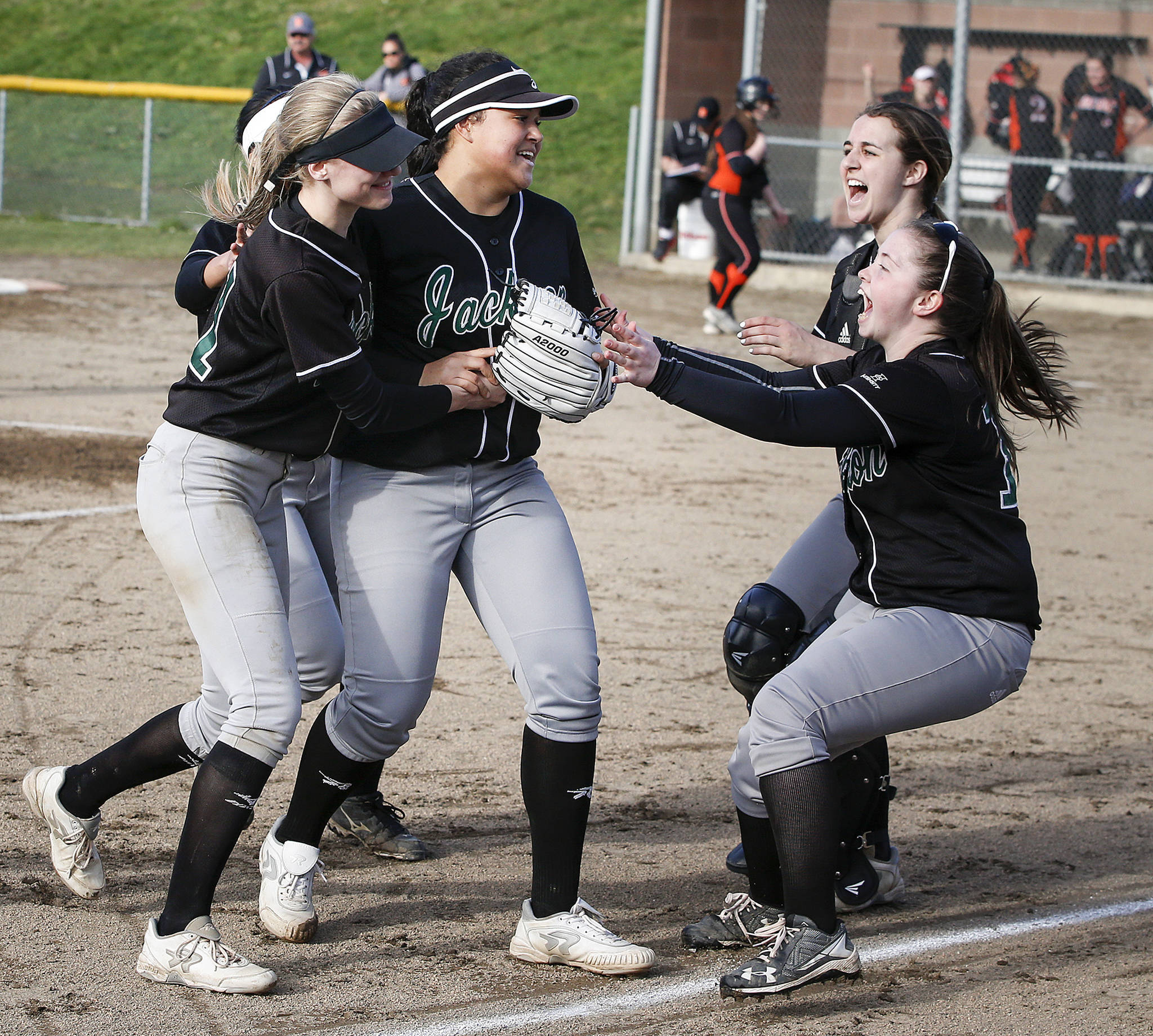 Jackson players Mollie Hickman (right) and Sam Mutolo (top right) celebrate with pitcher Iyanla Pennington (center left) and shortstop Kristina Day after Day made a catch and threw to first base for a double play to complete their victory over Monroe on March 31, 2017, at Jackson High School. (Ian Terry / The Herald)
