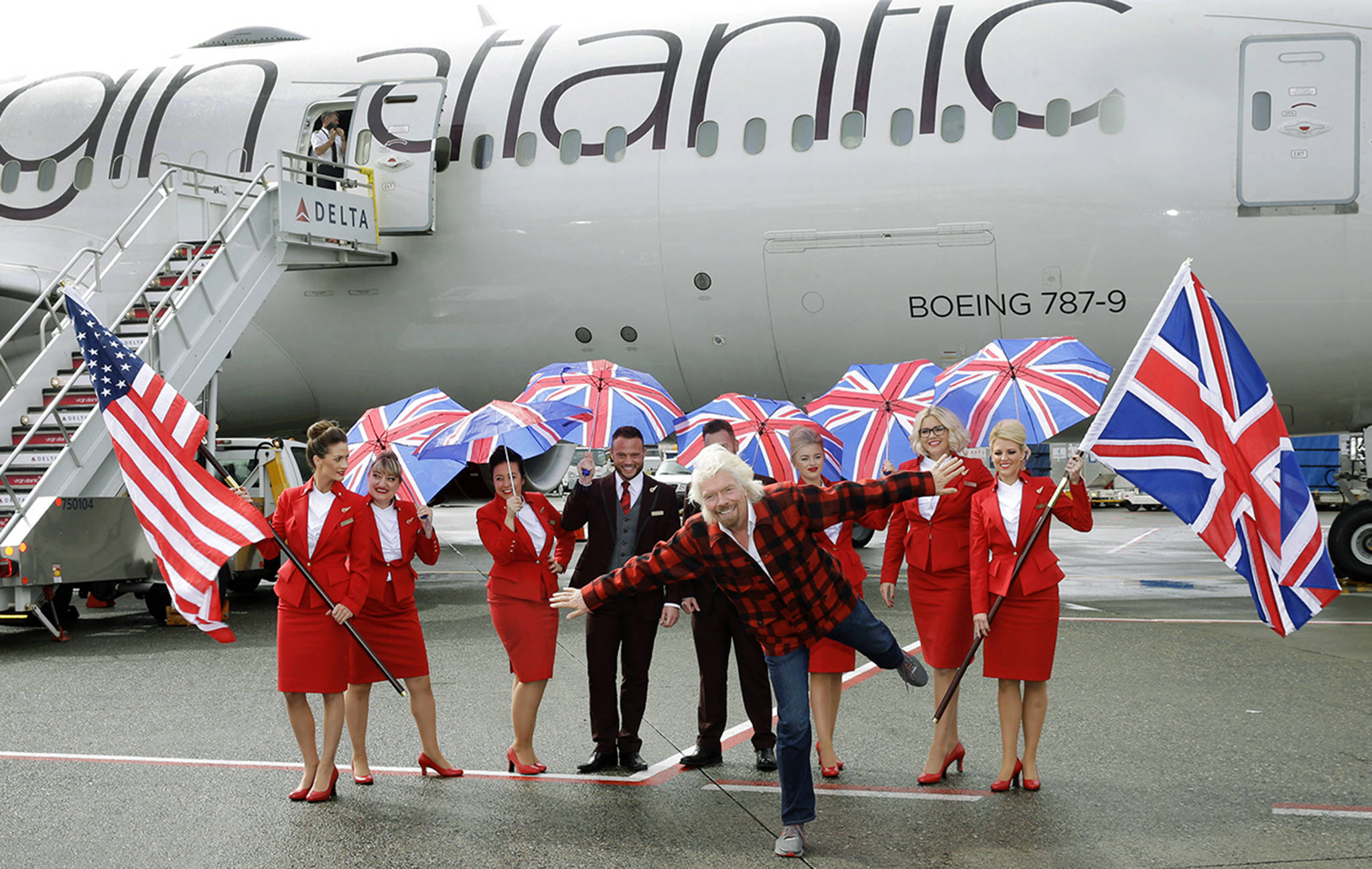 Richard Branson (center), founder of Virgin Atlantic and the Virgin Group, poses for a photo after he arrived on a flight from London to Seattle on Monday, March 27, at Seattle-Tacoma International Airport. (AP Photo/Ted S. Warren)