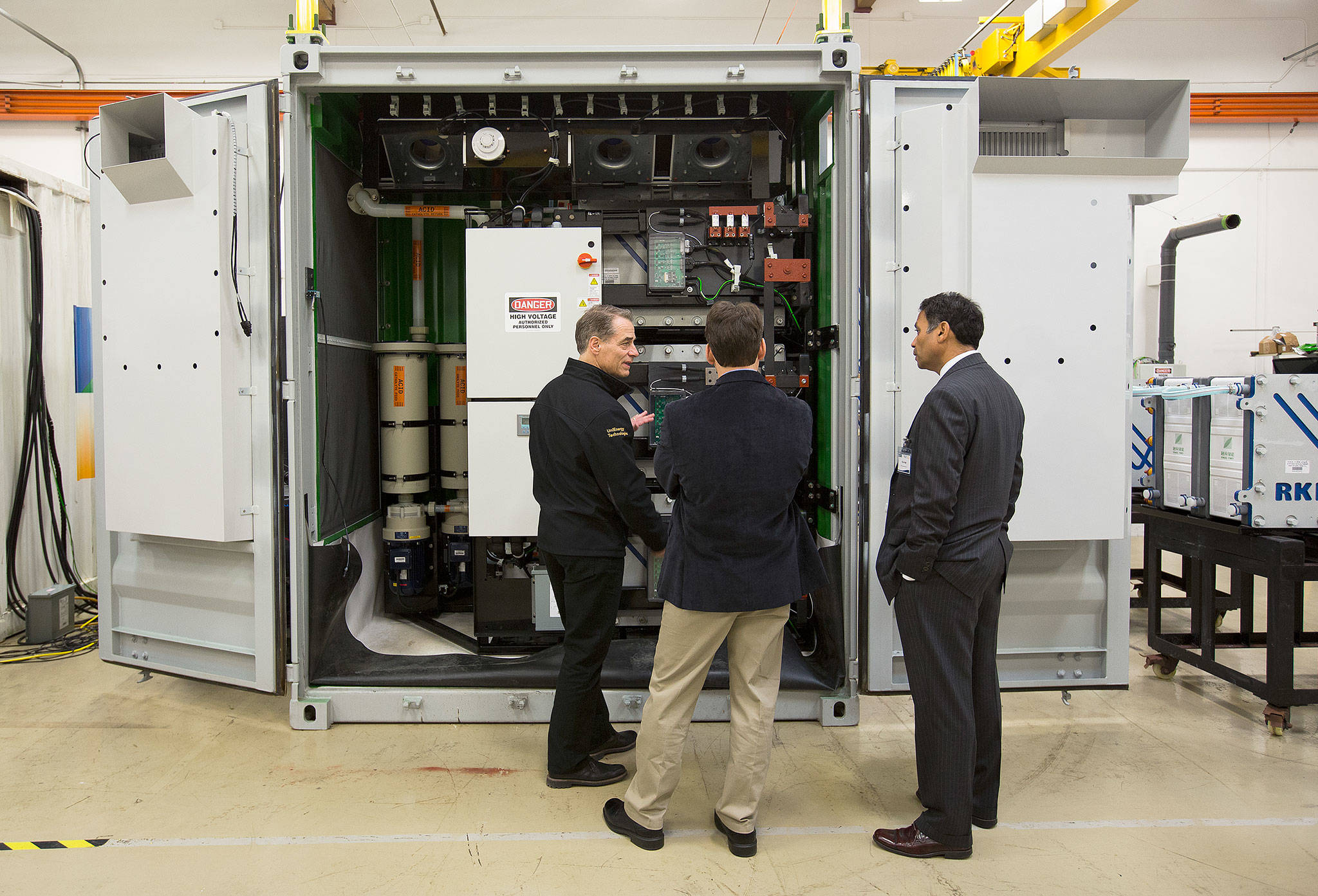 Brad Kell, UniEnergy Technologies vice president of Deployment and Field Service, explains how a flow-battery system works to two guests before a dedication ceremony for Snohomish Public Utility District’s second energy storage system Tuesday in Mukilteo. The system is the largest containerized vanadium flow battery in the world by capacity. The project is part of the PUD’s efforts to shape the energy storage market. This system was paid for in part with money from the Washington State Clean Energy Fund. (Andy Bronson / The Herald)