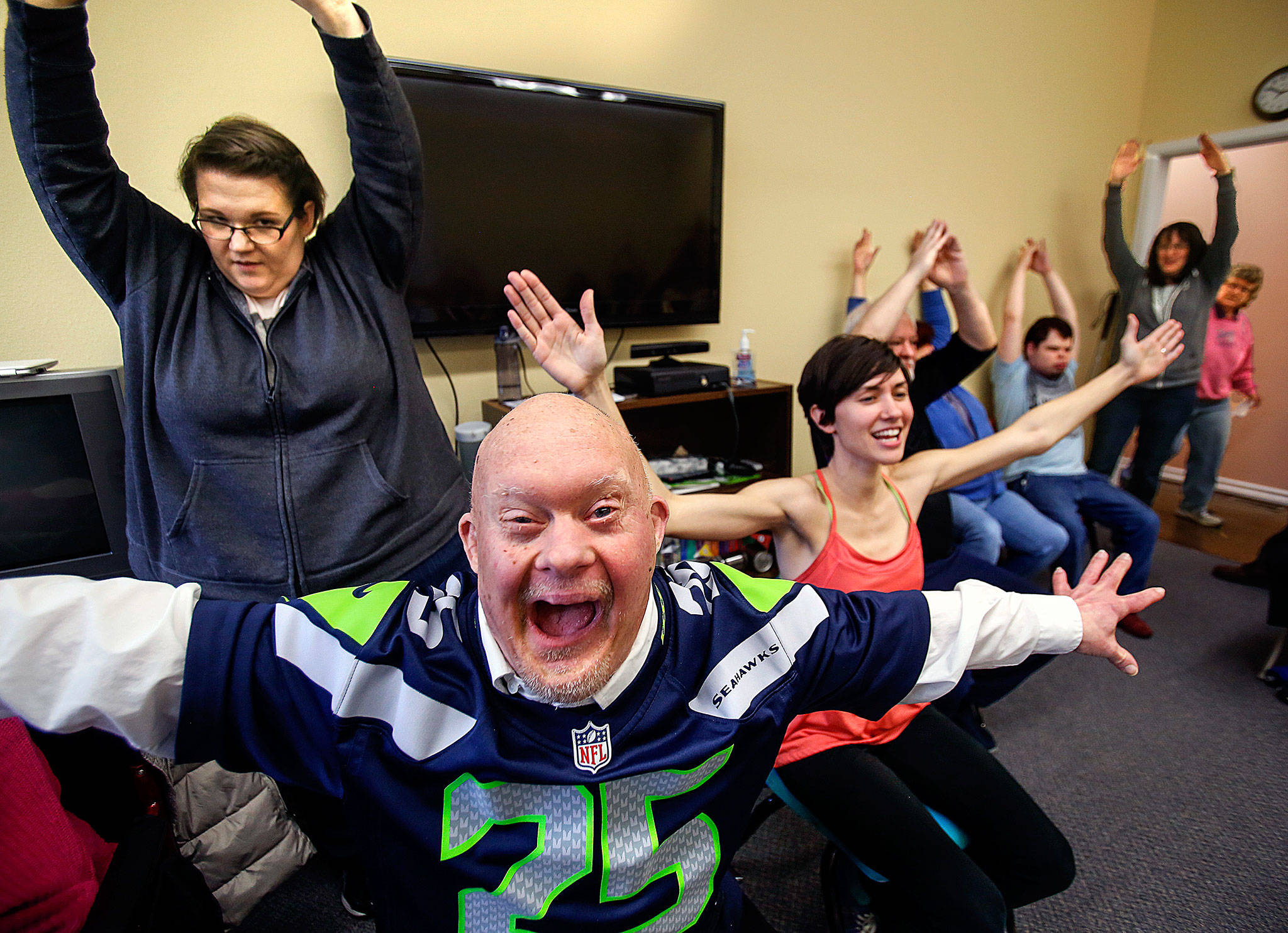 Larry Berg (nearest) enthusiastically helps Willow Place activity manager Rachel Hawkins (center) lead a modified yoga class early Tuesday at Quilceda Community Services in Marysville. (Dan Bates / The Herald)