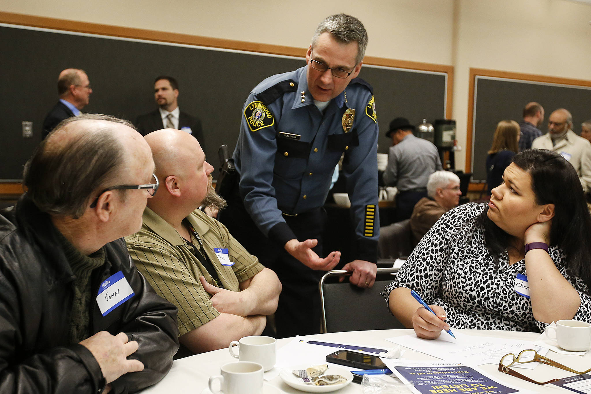 Tom Davis, Lynnwood’s Chief of Police, chats with a group including Phil (center left) and Chancey Homan (right), of Mercy Seat Christian Fellowship in Lynnwood, during the first “Cops and Clergy” meeting at the Lynnwood Convention Center on Feb. 8. The meeting was meant to spur conversation and partnership between local law enforcement and faith leaders in the community. (Ian Terry / The Herald)