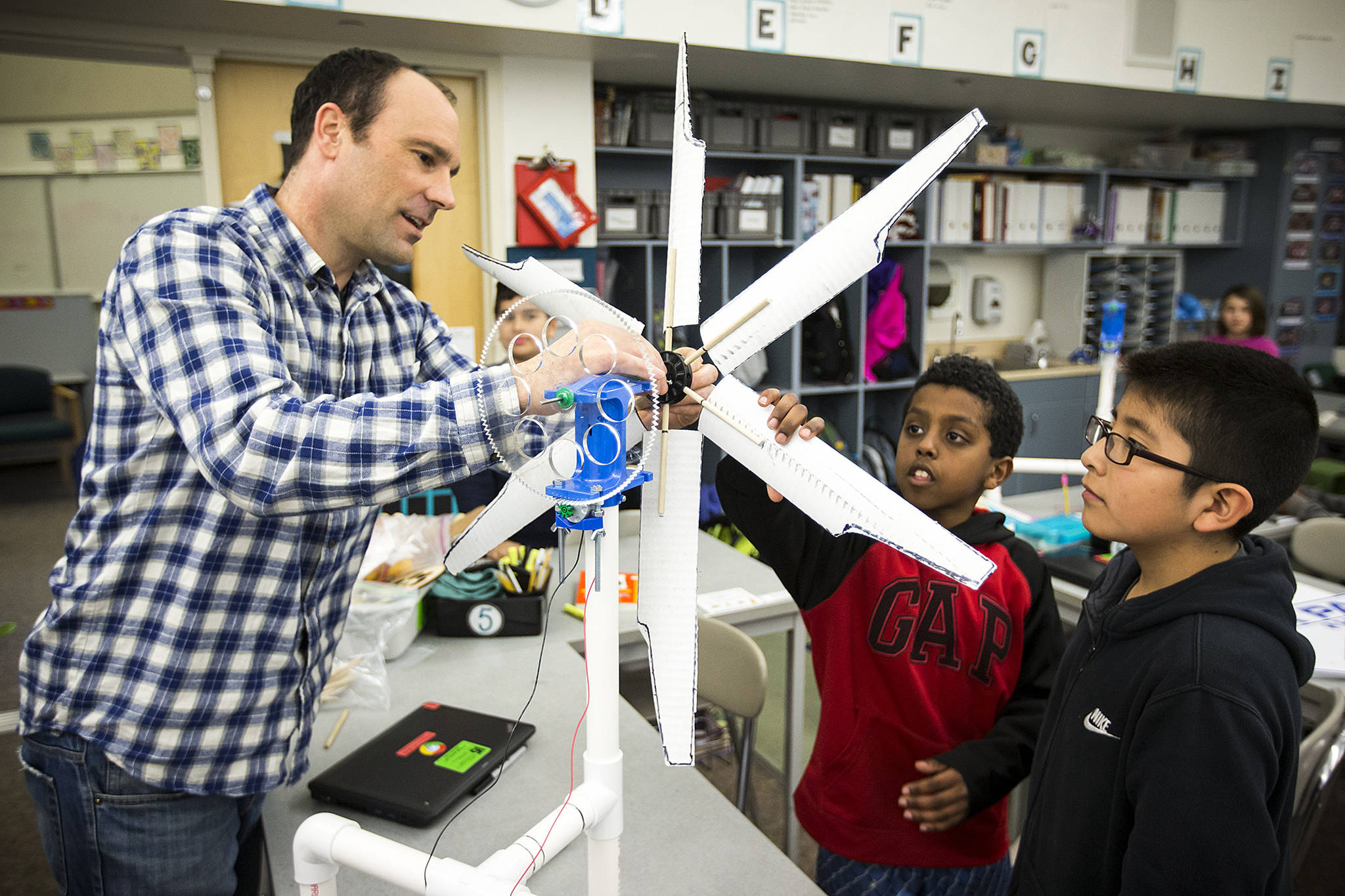 Students Noah Henok (center right), 11, and Cris Martinez, 11, get help attaching the blades of their homemade wind turbine from teacher Jody Wallis at Chase Lake Elementary School in Edmonds on Tuesday. Fourth- and fifth-graders at the school are learning about renewable energy through a national program called the KidWind Challenge. (Ian Terry / The Herald)