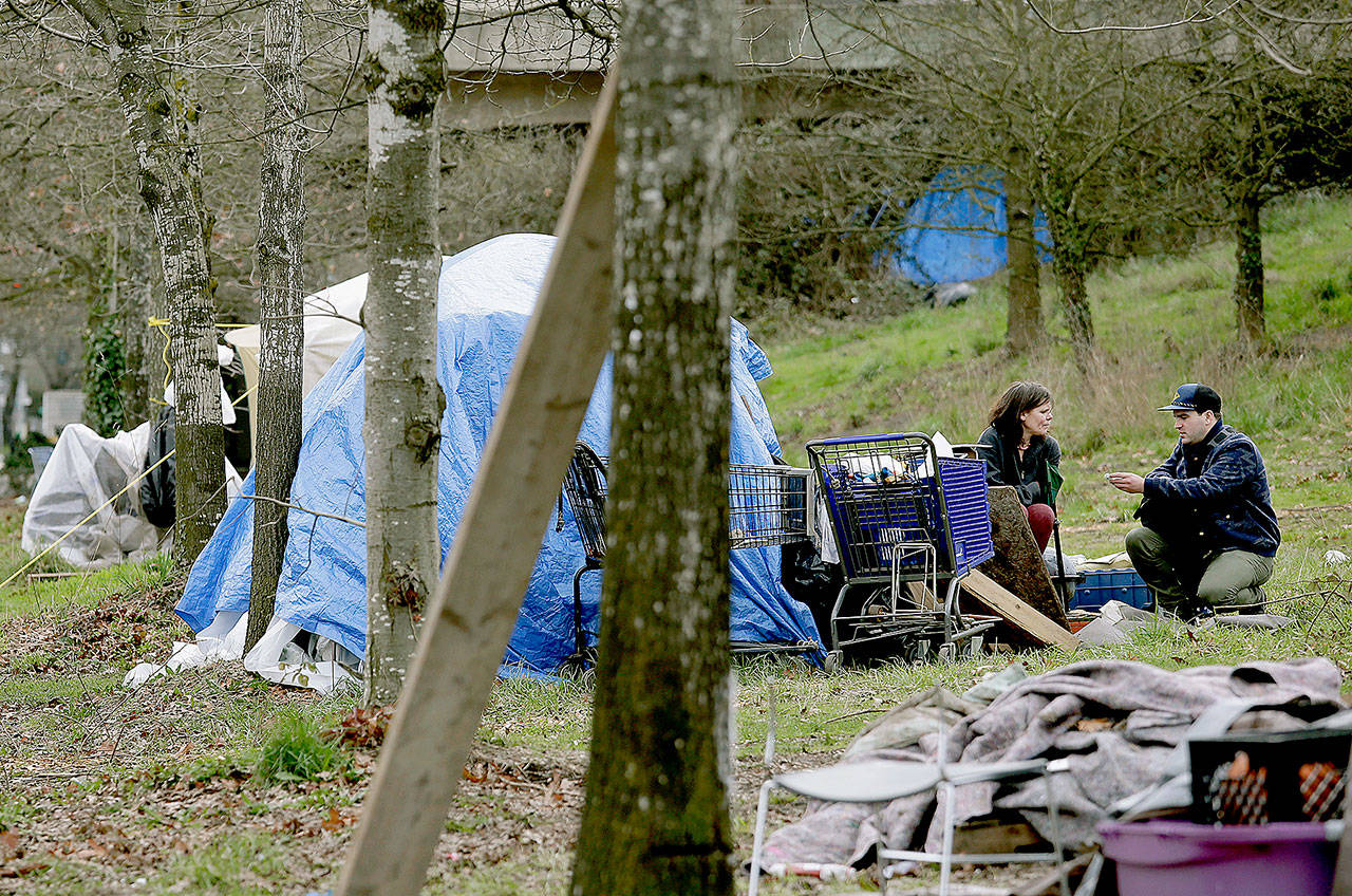 Nurse Eric Seitz (right) talks with a camper living in Seattle. He is part of a new team of outreach workers and police officers that go out and connect homeless people to services. (AP Photo/Elaine Thompson)