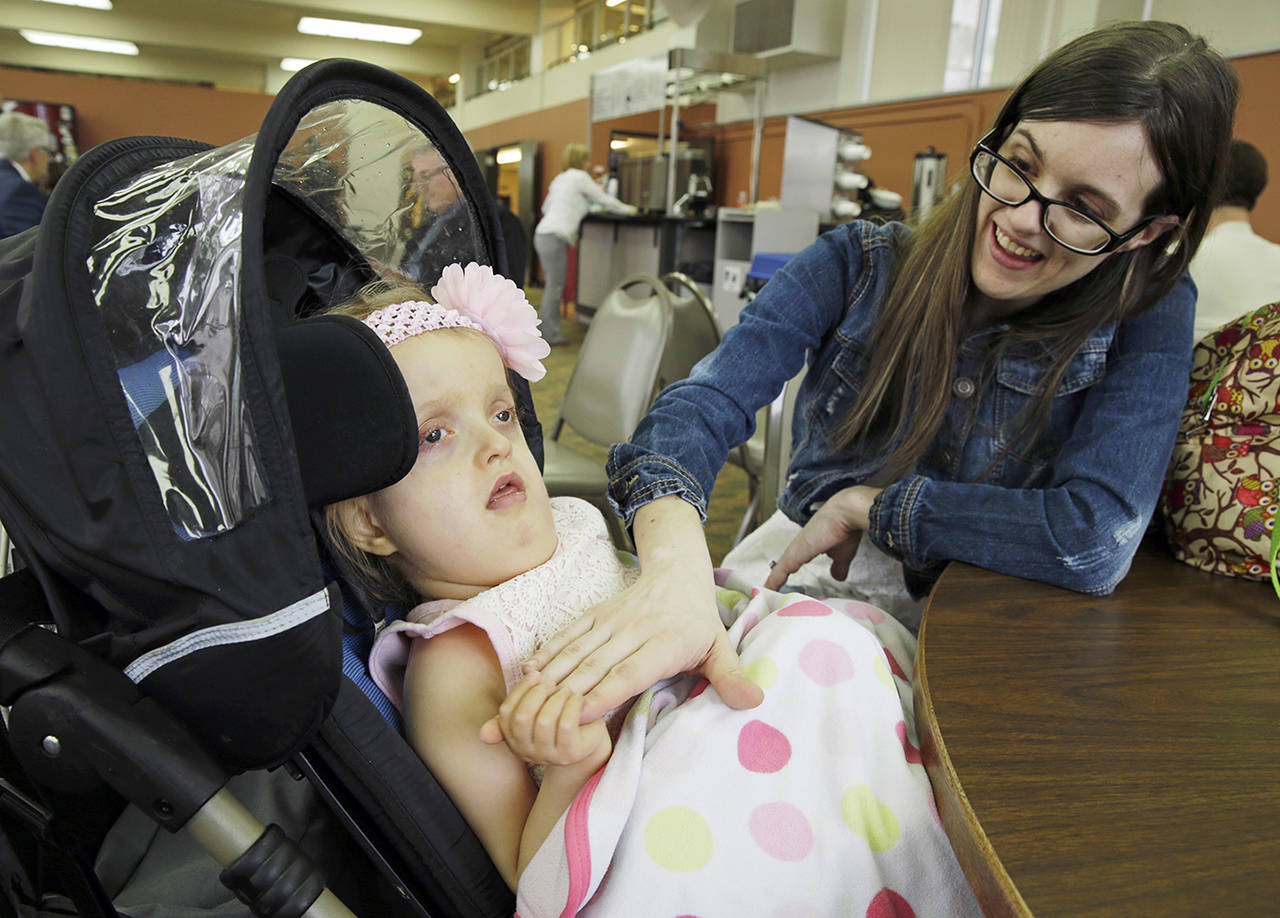 Meagan Holt comforts her daughter Maddie after they attended a March 28 hearing at the Capitol in Olympia for House Bill 1060, which would allow parents or guardians to administer medical marijuana to children while at school or on a school bus. (AP Photo/Ted S. Warren)