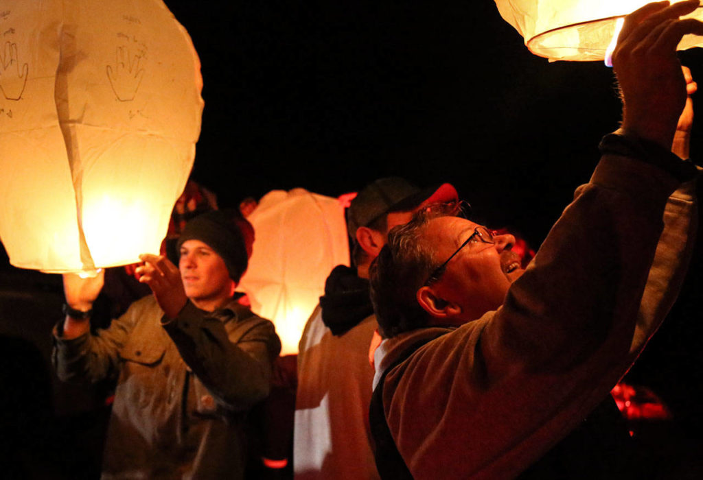 Baylee and Frank Hadaway work Wednesday evening to launch lanterns in memory of those who died in the Oso mudslide. (Kevin Clark / The Herald)
