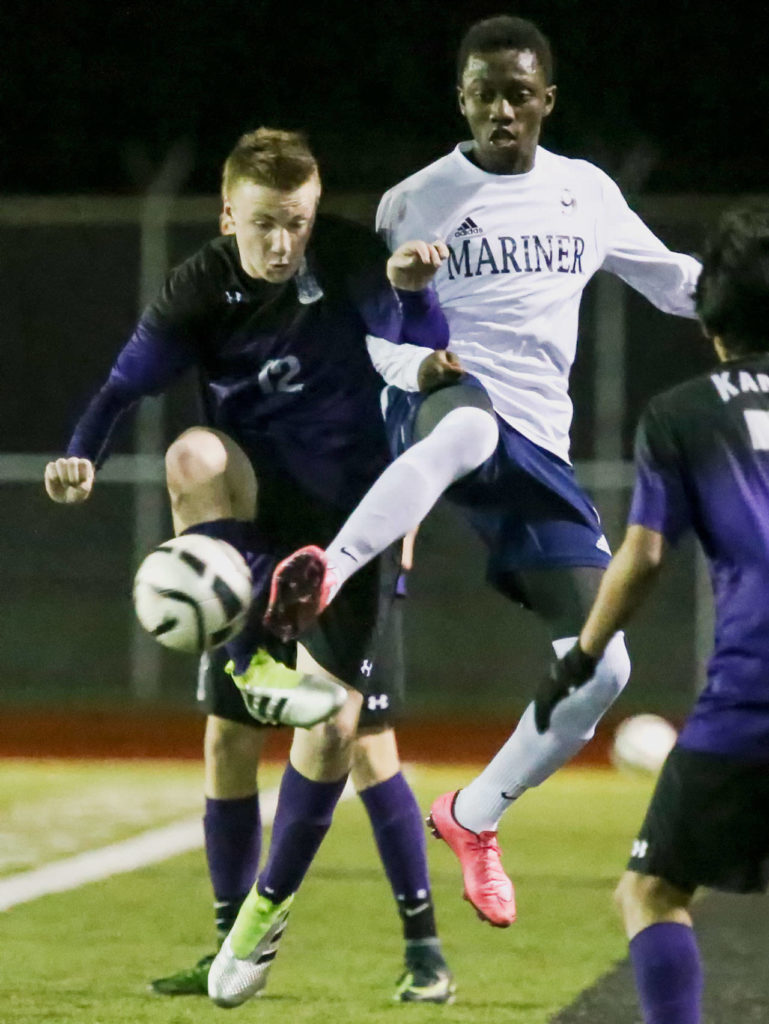Kamiak’s Sebastian Munroe, left, and Mariner’s Bakary Dibba vie for a loose ball in the first half Friday night at Mariner High on March 24, 2017. (Kevin Clark / The Herald)

