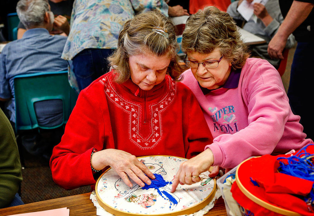 Karen Harper (right) assists her sister, Leslie Venables, with sewing Tuesday at Quilceda Community Services. A founding board member, Harper wanted to care for her sister and has done so from the beginning. (Dan Bates / The Herald)
