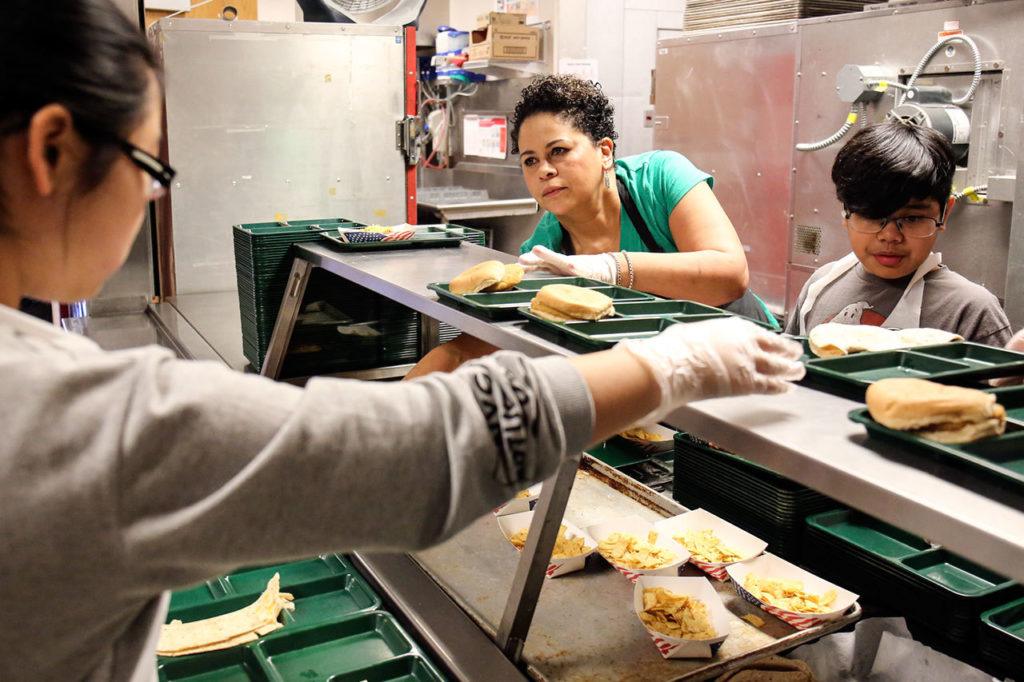 Grace Chang, Lisa Gaines and Kowin Edward prepare for first lunch Thursday morning at Challenger Elementary School in Everett. (Kevin Clark / The Herald)

