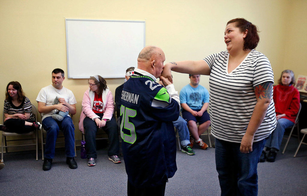 QCS caregiver Jamie Denton is rewarded with chivalry from Larry Berg for being a good sport Tuesday following a yoga program. (Dan Bates / The Herald)
