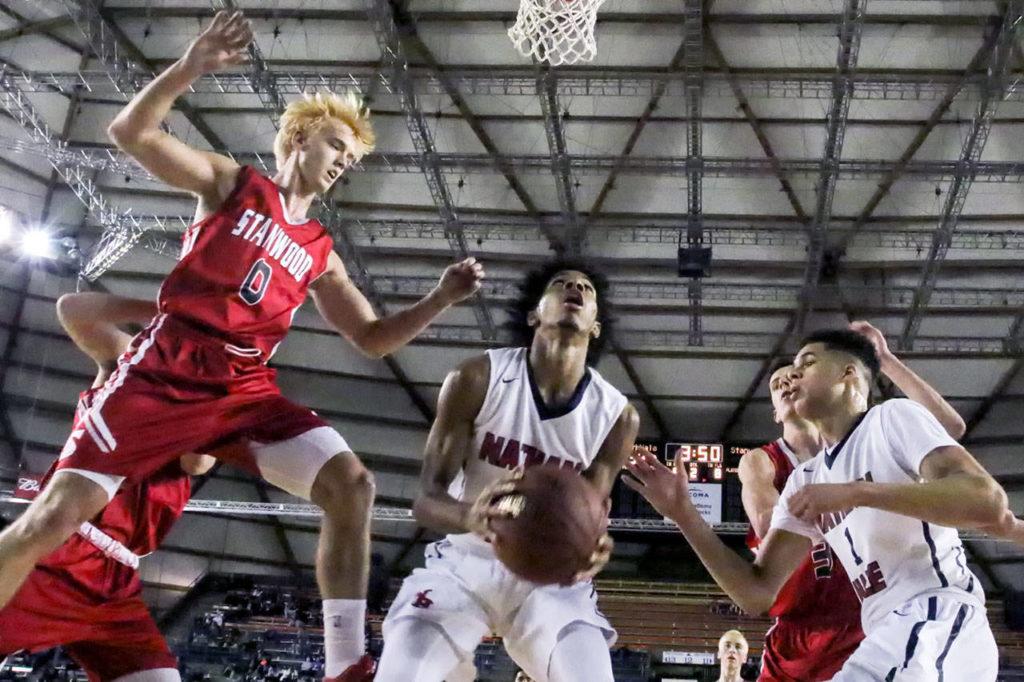 Nathan Hale’s P.J. Fuller (center) gathers a rebound as Stanwood’s A.J. Martinka (0) soars through the air during a 3A state tournament game March 2, 2017, at the Tacoma Dome. (Kevin Clark / The Herald)
