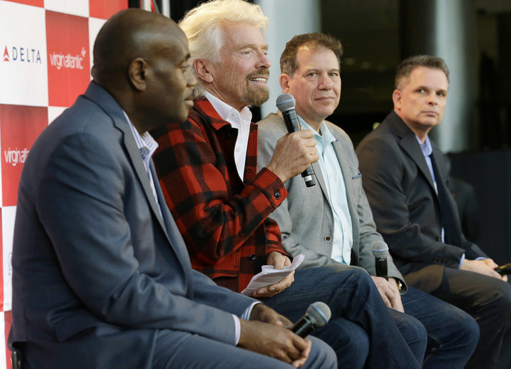 Richard Branson (second from left), founder of Virgin Atlantic and the Virgin Group, speaks at a news conference as he sits with Lance Lyttle (left), Managing Director of the Port of Seattle; Craig Kreeger (second from right), CEO of Virgin Atlantic; and John Caldwell (right), Seattle vice president of Delta Air Lines, on Monday, March 27, at Sea-Tac Airport. (AP Photo/Ted S. Warren)
