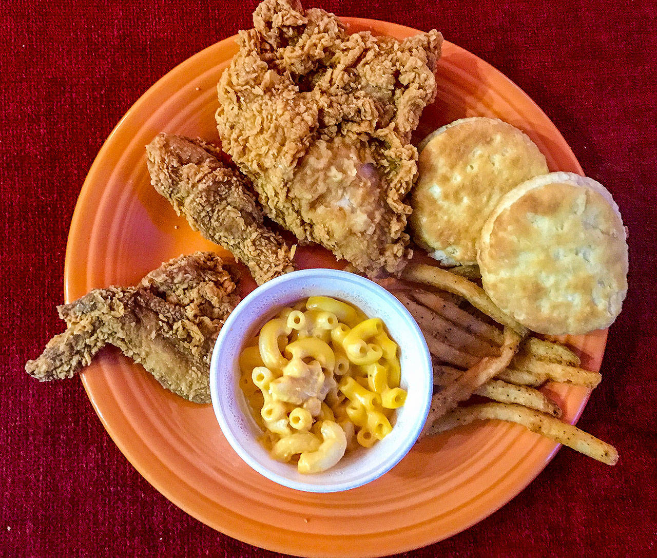 A carryout from Popeyes Louisiana Kitchen displayed on a plate at home has New Orleans style chicken, buttermilk biscuits, Cajun fries and macaroni and cheese. (Andrea Brown/The Herald)