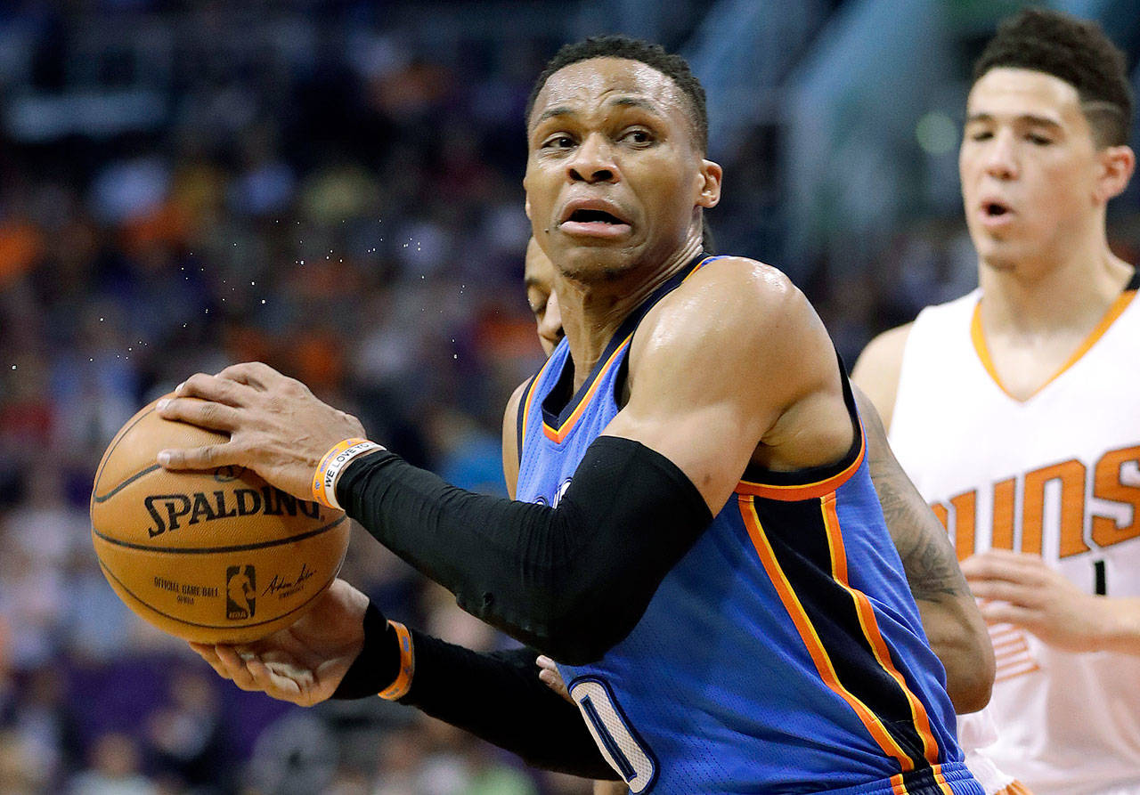 Oklahoma City’s Russell Westbrook (0) spins around Phoenix’s Devin Booker during the first half of the Suns’ 120-99 win over the Thunder on Friday in Phoenix. Westbrook became the second player to average a triple-double for a full season in the loss. (AP Photo/Matt York)