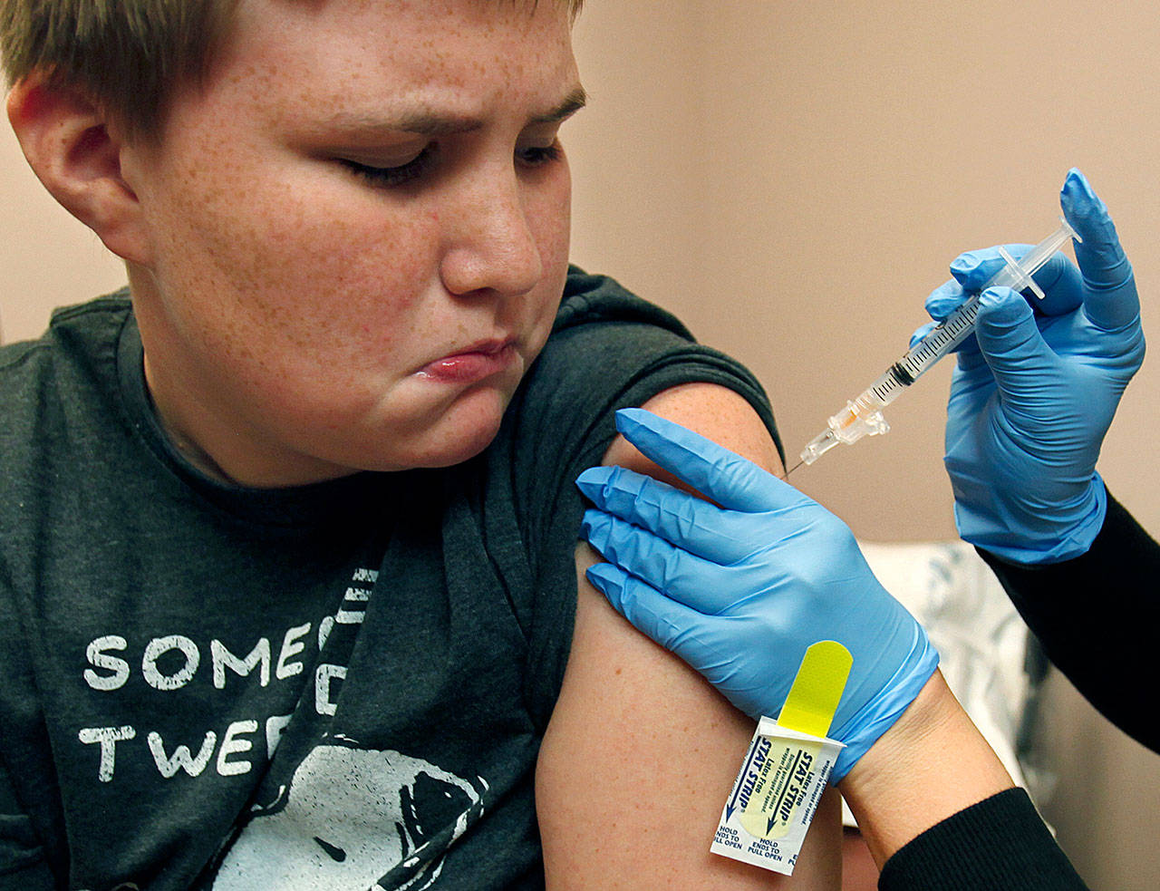 Benjamin Munn, then 12, of Sultan, watches the needle as medical assistant Megan Smith gives him a shot of HPV vaccine at the Providence Medical Group in Monroe in July 2013. The vaccine, which now requires just a two-shot course for those 14 and younger, is recommended as most effective for girls and boys ages 11 and 12. (Dan Bates / Herald file photo)