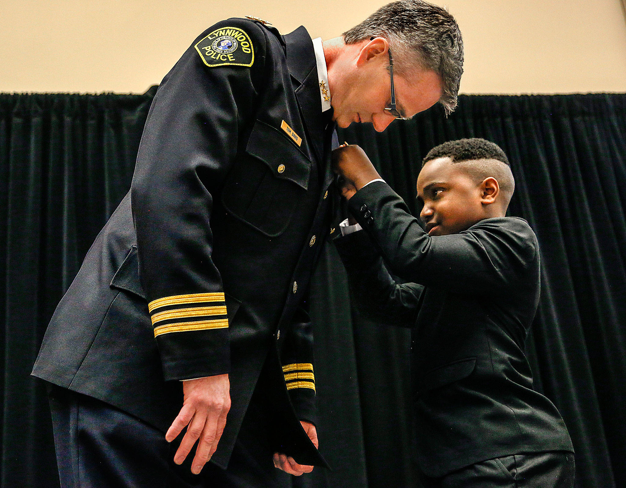 Tyson Webster, 9, of Shoreline, has the honor of pinning the badge on Lynnwood’s new chief of police, Tom Davis, on Tuesday during a celebration at the Lynnwood Convention Center. (Dan Bates / The Herald)